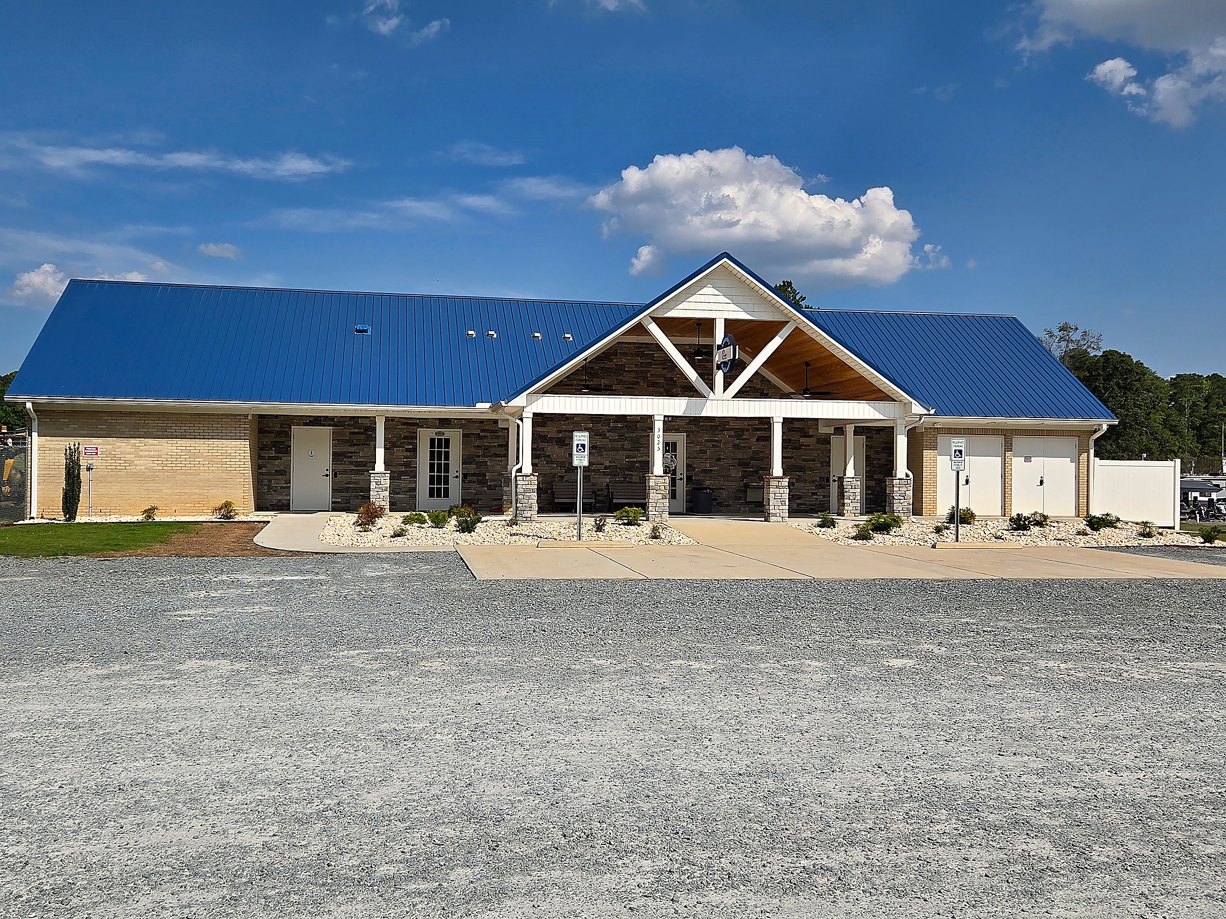Commercial building with blue metal roof, stone veneer and covered entry by Tucker Built Construction