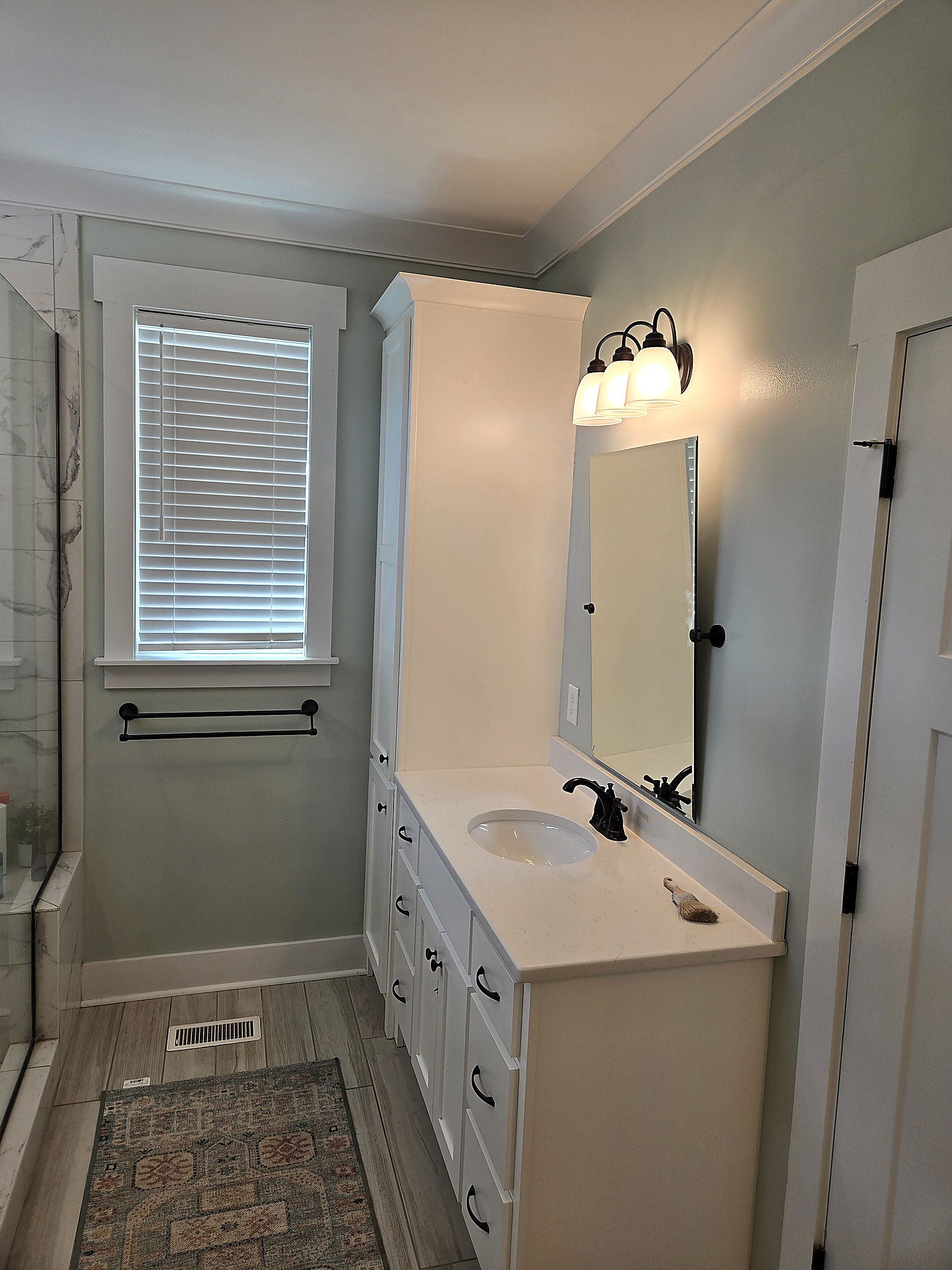 Bathroom remodel with white vanity and linen tower, quartz countertop, tile shower and trim by Tucker Built Construction