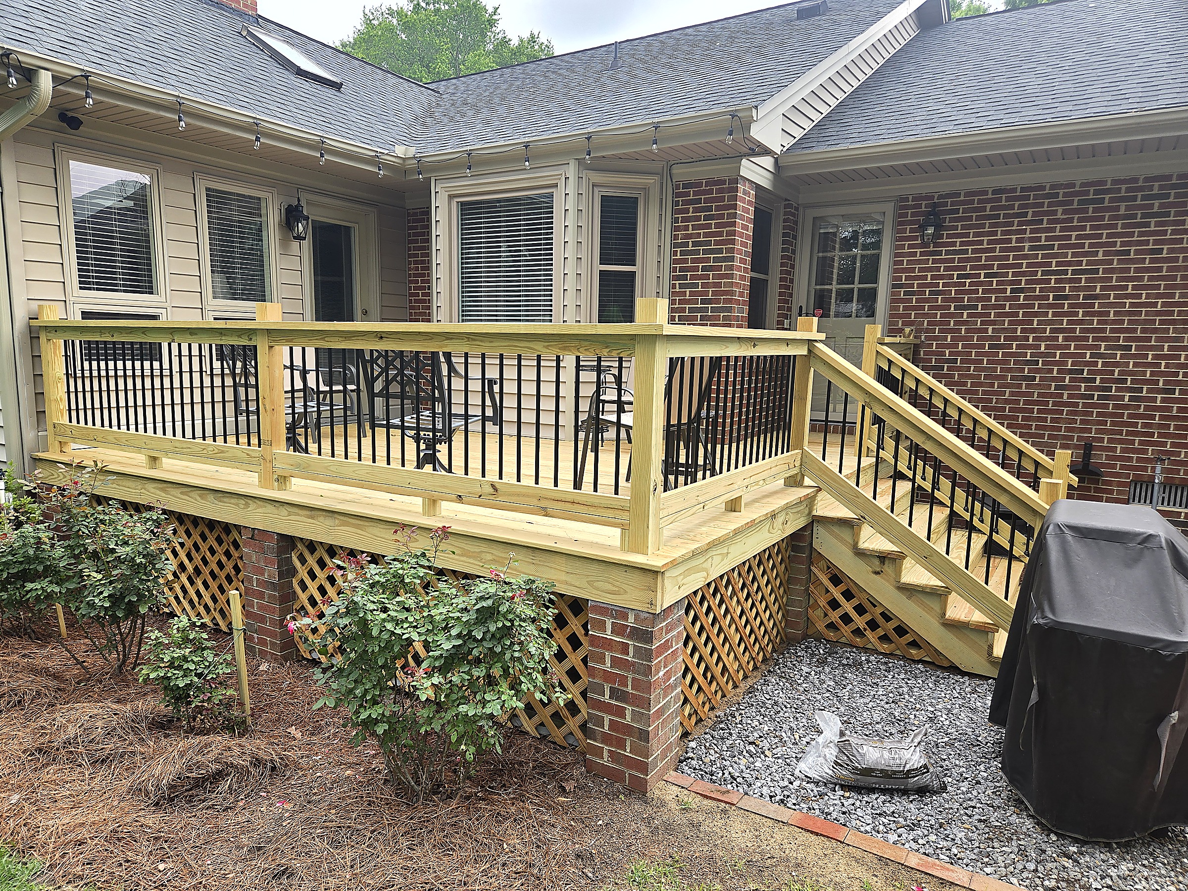 New pressure-treated deck with black metal balusters and stairs by Tucker Built Construction