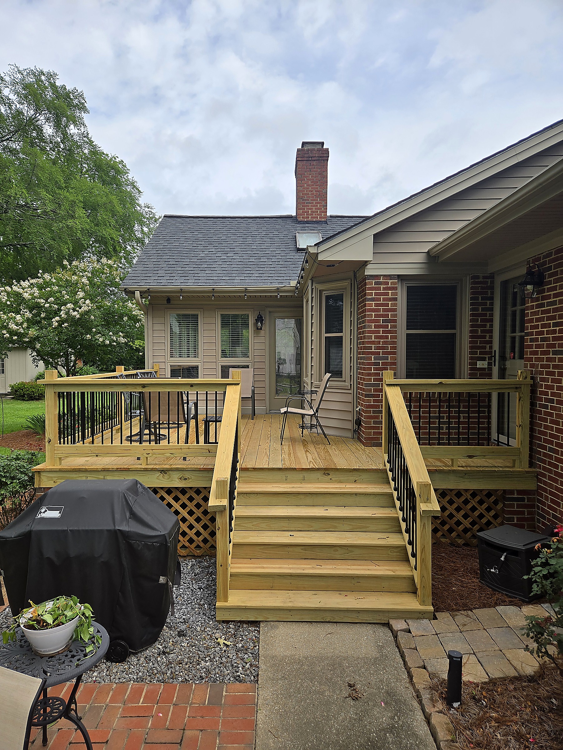 New pressure-treated deck with wide stairs and black metal balusters by Tucker Built Construction