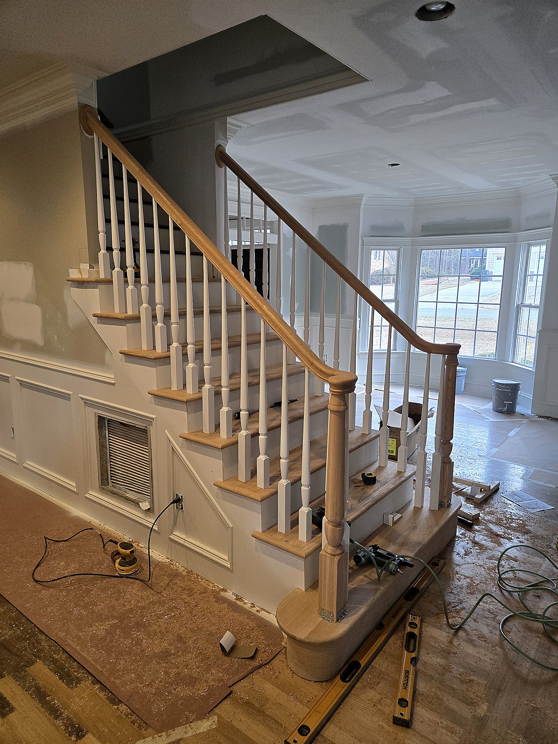 Oak staircase and white balusters being installed during a home renovation by Tucker Built Construction