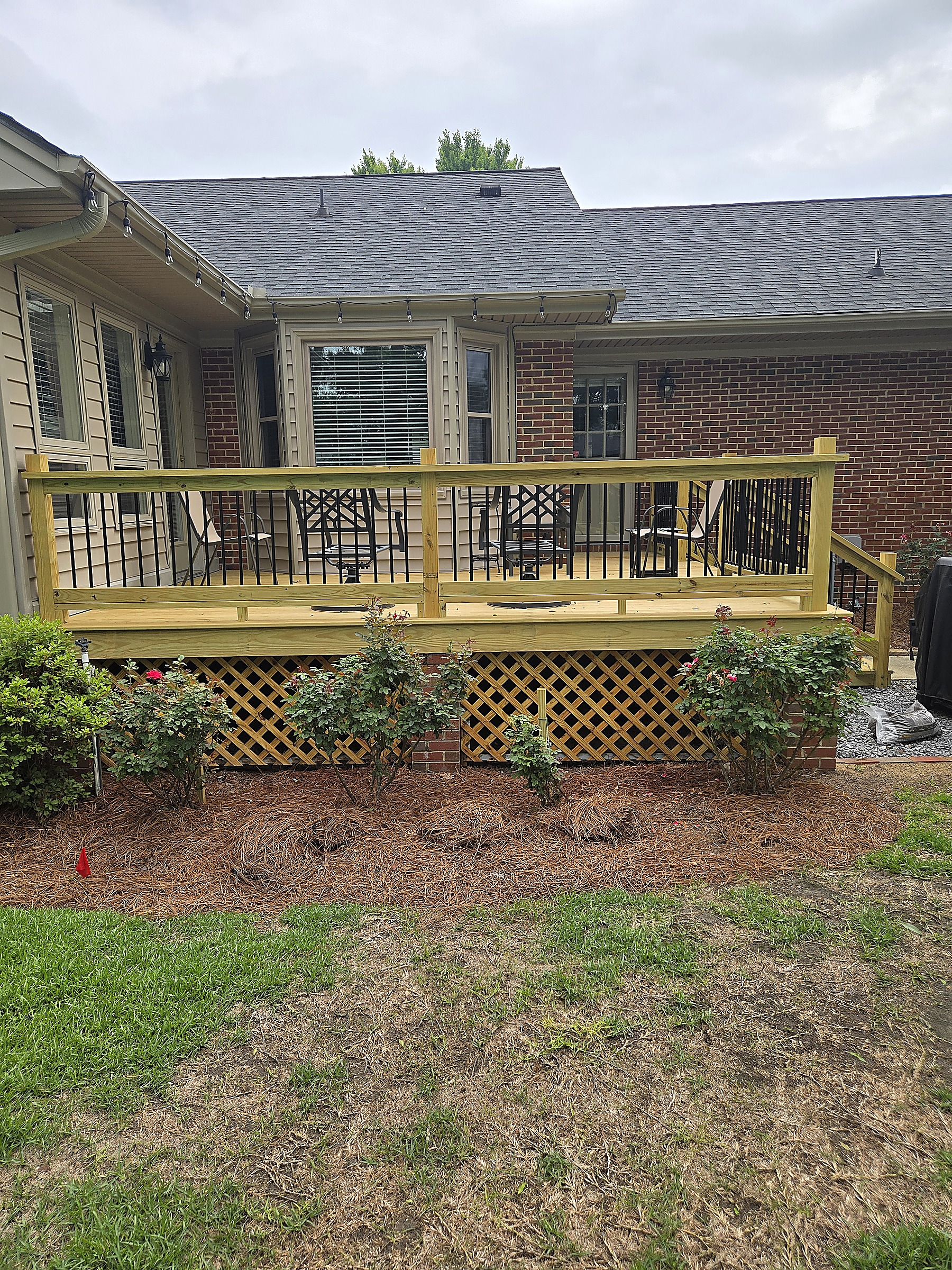 Front view of a new deck with lattice skirting and landscaped bed by Tucker Built Construction