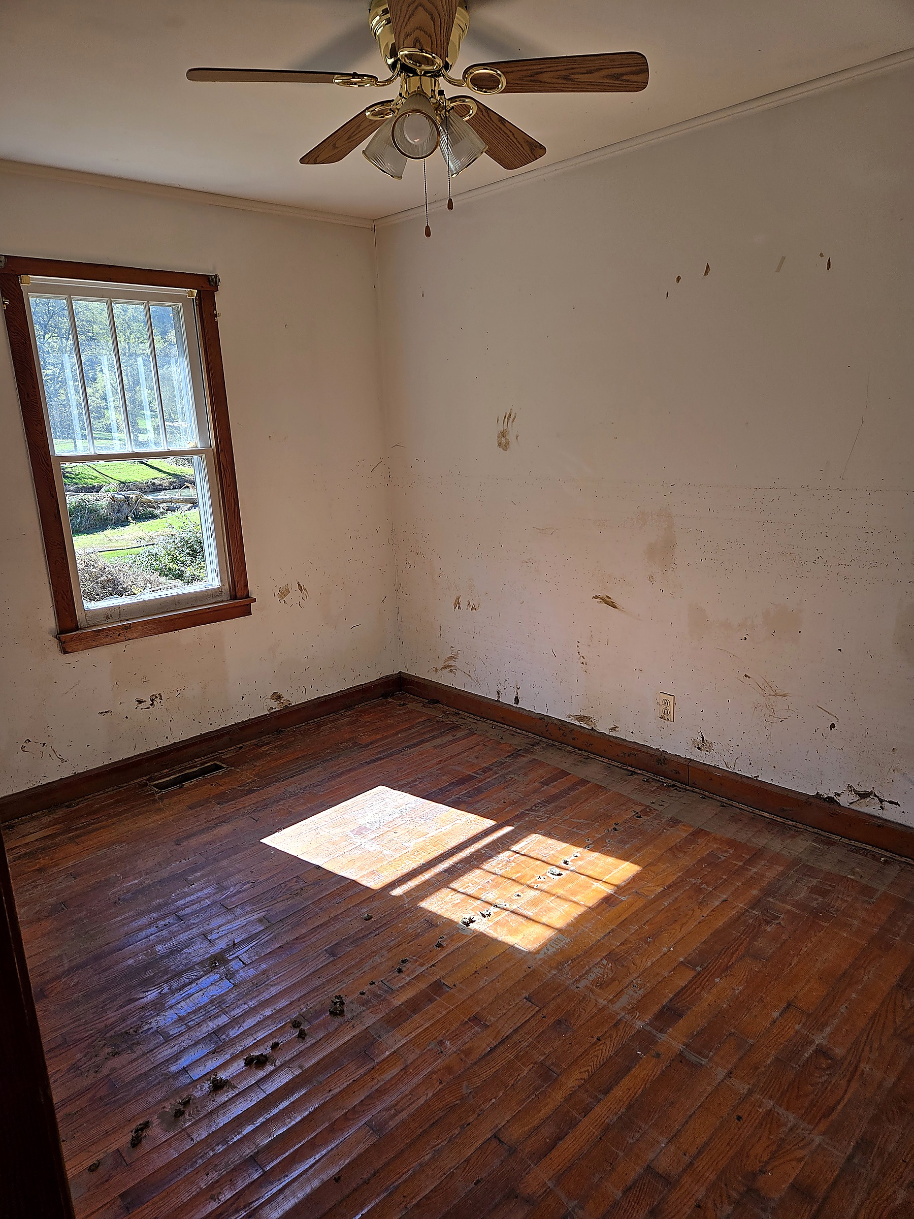 Bedroom with mud and water damage on the walls and floor before renovation