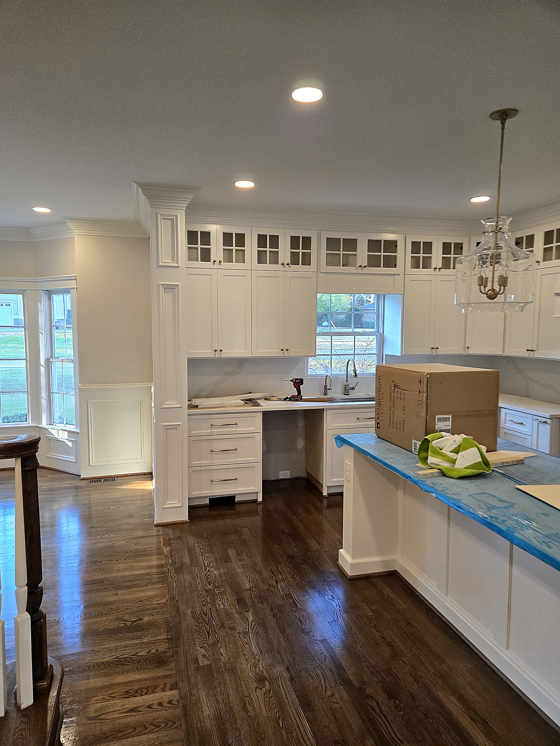 Kitchen remodel with white shaker cabinets, glass-front uppers, custom trim and hardwood floors by Tucker Built Construction