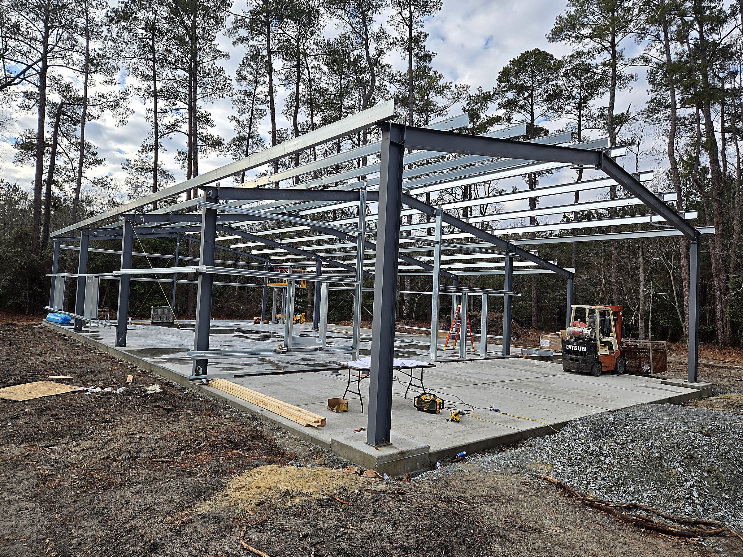Steel frame of a metal building being erected on a new concrete slab by Tucker Built Construction