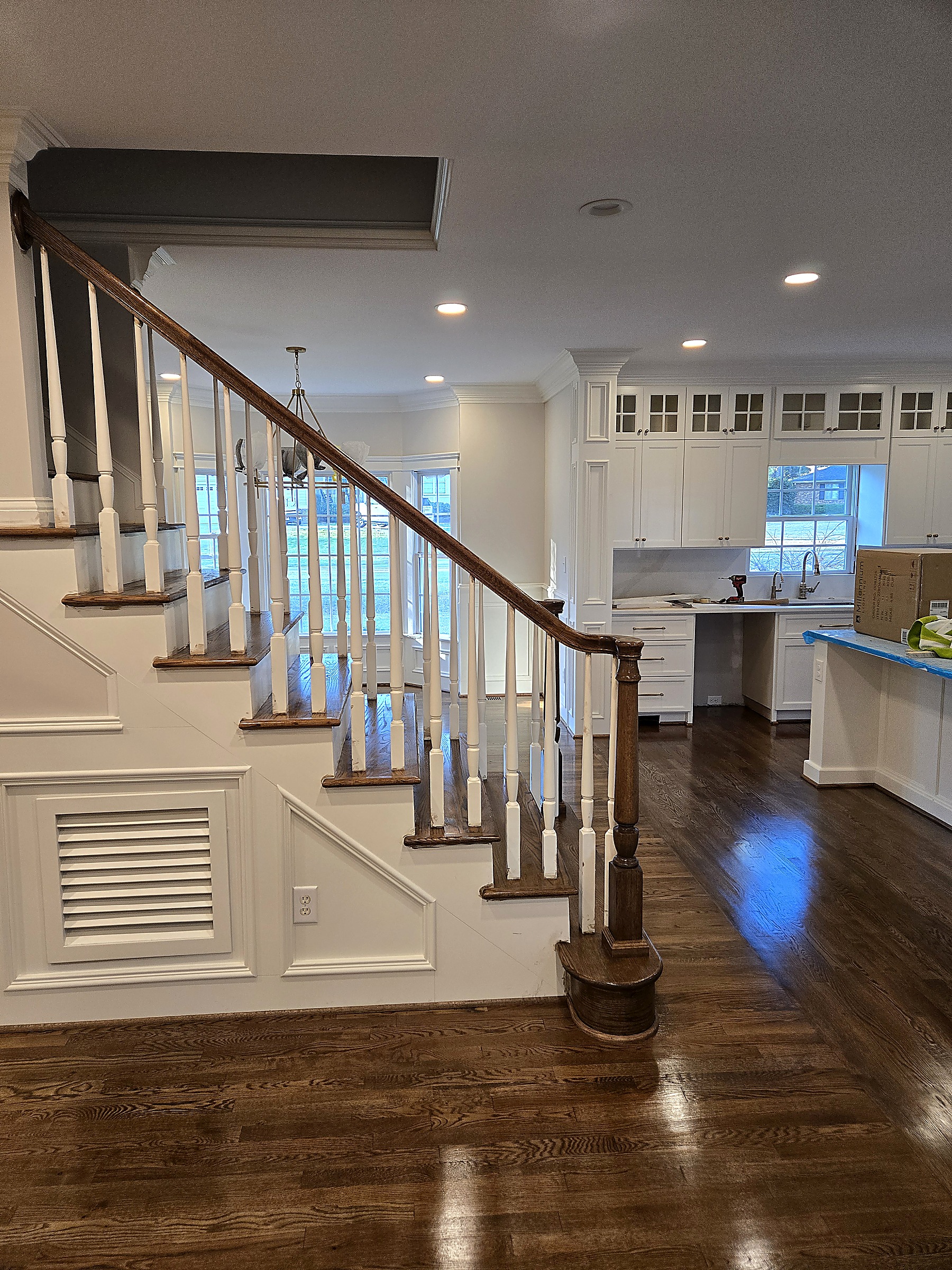 Staircase with oak handrail, white balusters and custom wainscoting trim by Tucker Built Construction