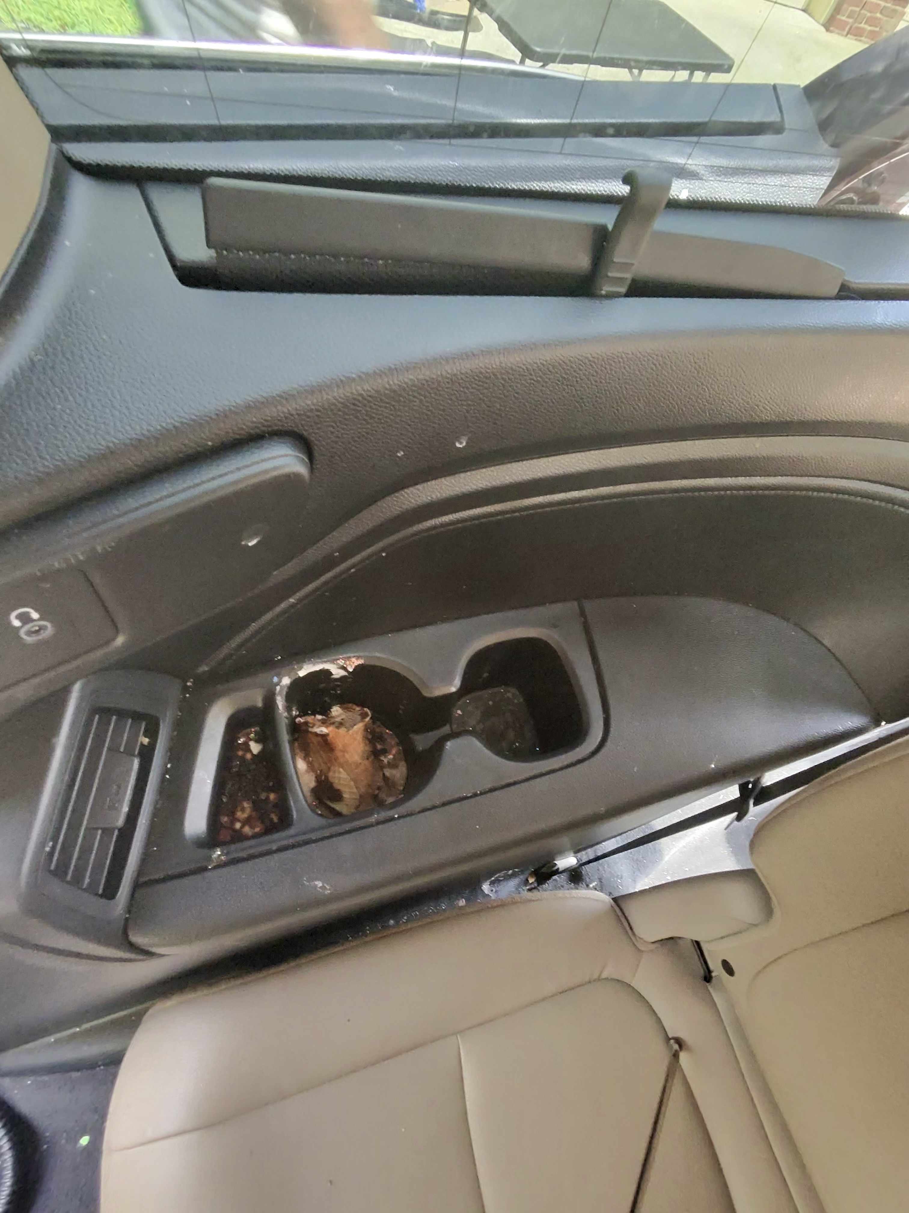 Vehicle center console and cup holder area with visible soil before detailing