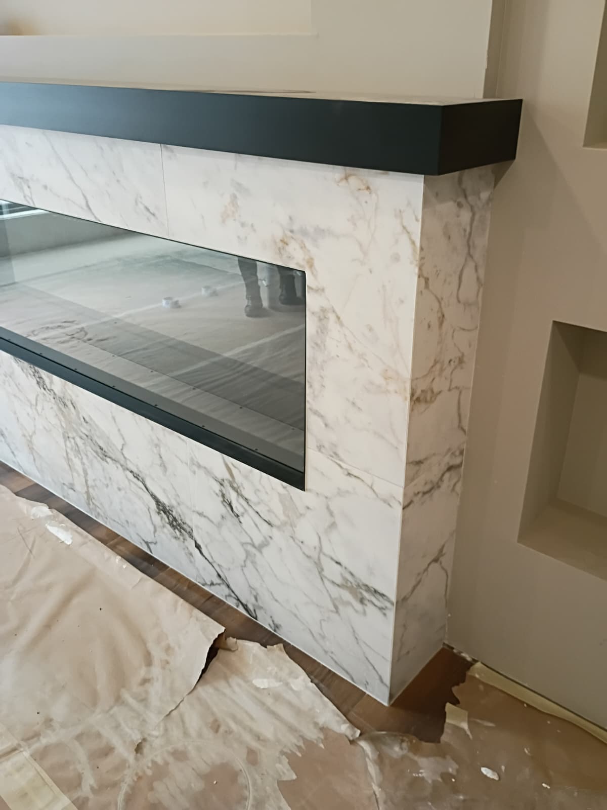 Book-matched Calacatta gold veined porcelain marble fireplace surround with sleek black mantle ledge crafted in Easley SC