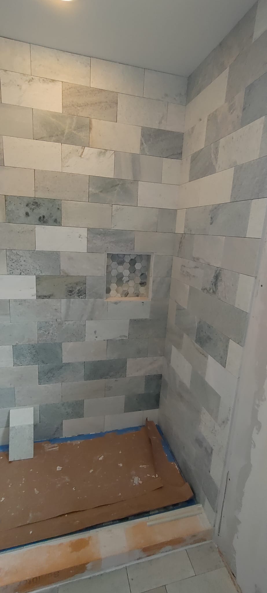 Natural veined marble subway tile shower walls with custom inset hexagon mosaic niche built by Roberto Vicente in Easley SC