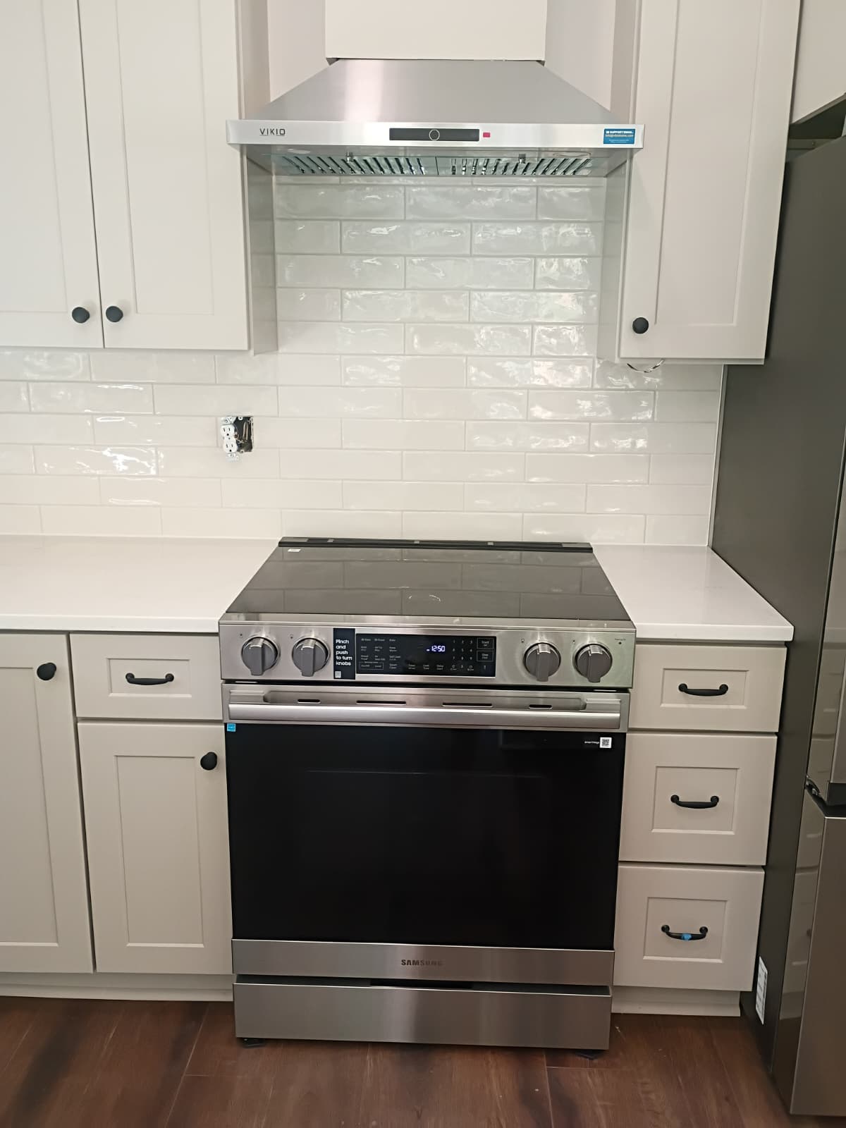 Modern kitchen renovation with white shaker cabinets, subway tile backsplash, and stainless range hood completed by Rvicente Remodeling LLC in Greenville SC