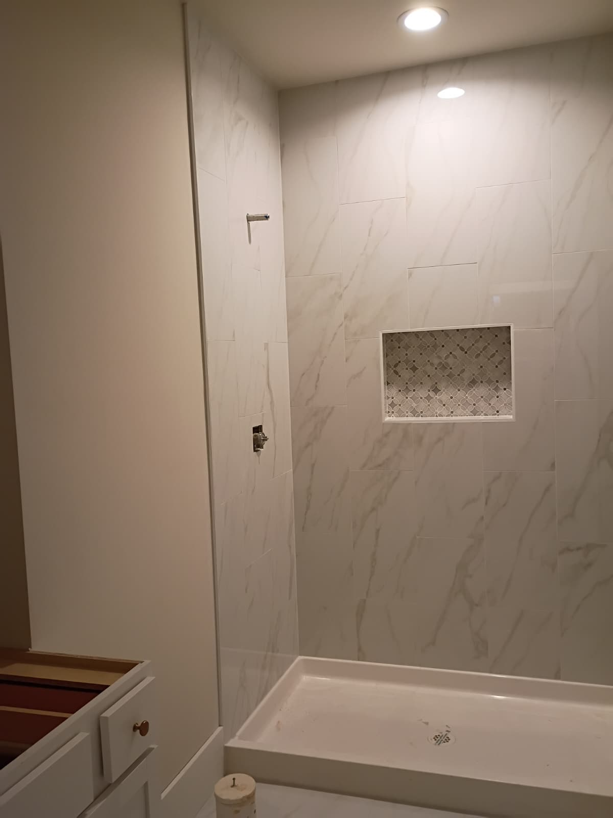 Polished marble shower with geometric patterned mosaic niche and low profile pan installed by Rvicente Remodeling LLC in Clemson SC