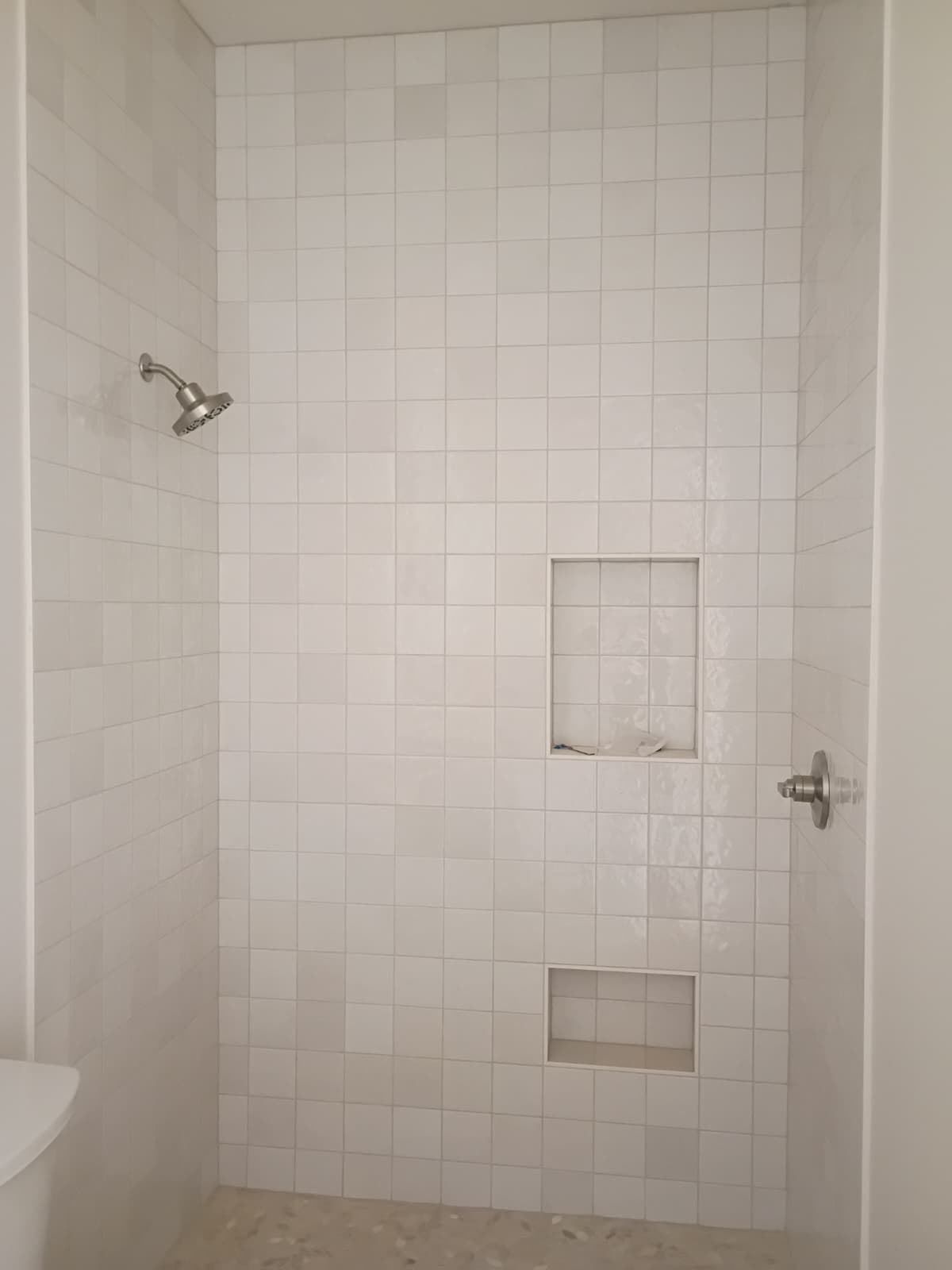 Floor-to-ceiling white square tiled shower with dual upper and lower recessed niches and brushed nickel hardware in Simpsonville SC