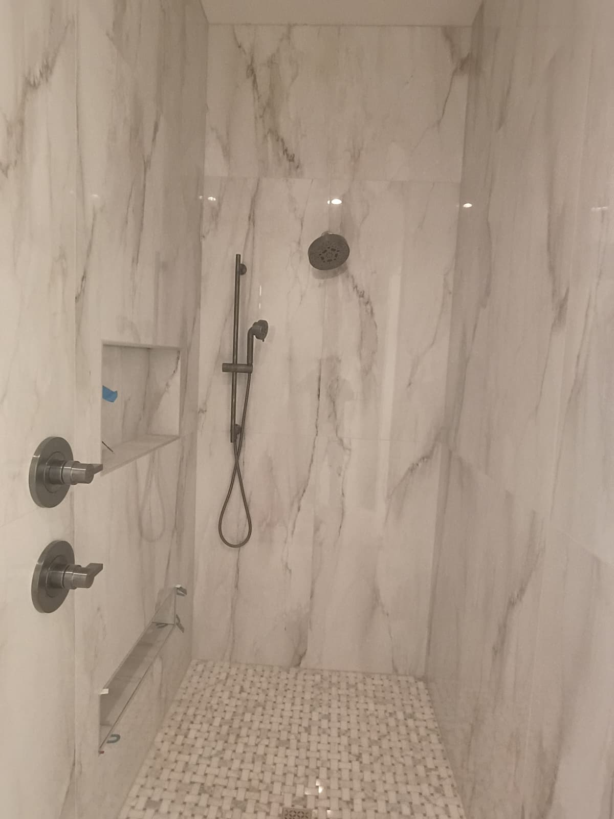Luxury Calacatta marble slab tile walk-in shower with marble basketweave mosaic floor, dual shower control valves, and slide-bar handheld sprayer in Spartanburg SC