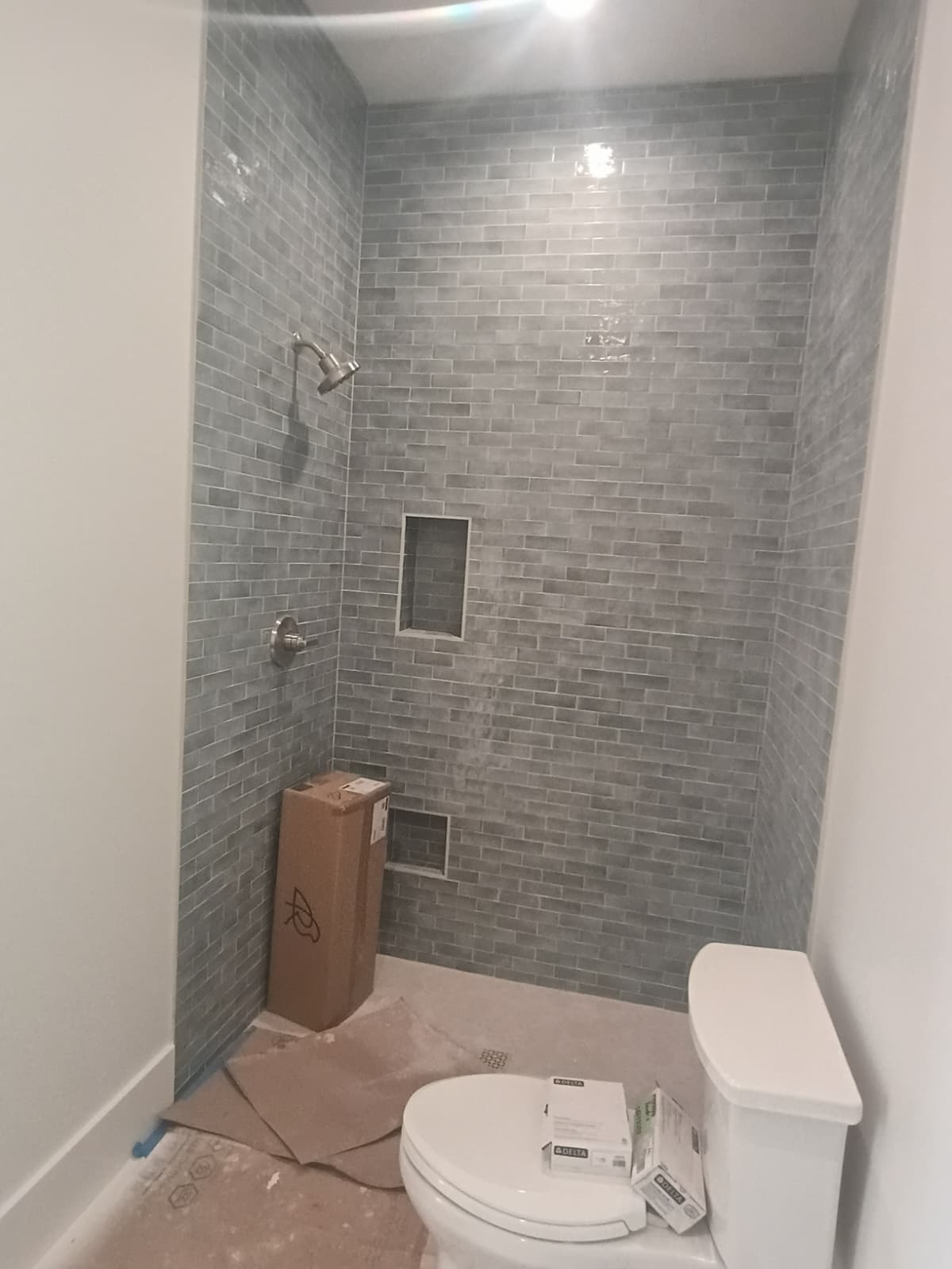 Walk-in shower tiled in textured gray subway tile with dual recessed niches and Delta fixtures by Rvicente Remodeling LLC in Easley SC