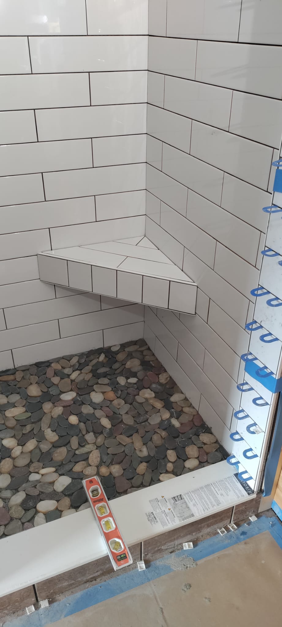 Hand-laid river rock pebble shower floor with level curb threshold by Rvicente Remodeling LLC in Simpsonville SC