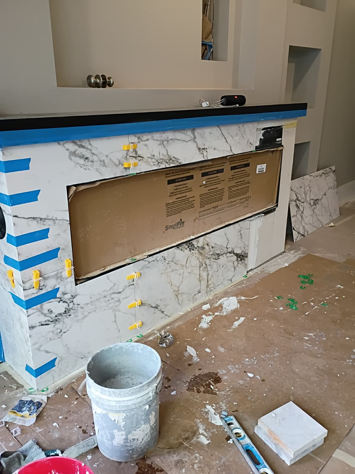 Simplifire modern electric fireplace tile surround installation with leveling wedge system by Roberto Vicente in Pickens SC