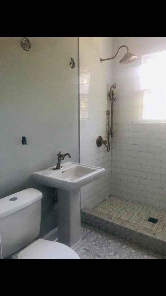Baño terminado con ducha de azulejo blanco, lavabo y sanitario