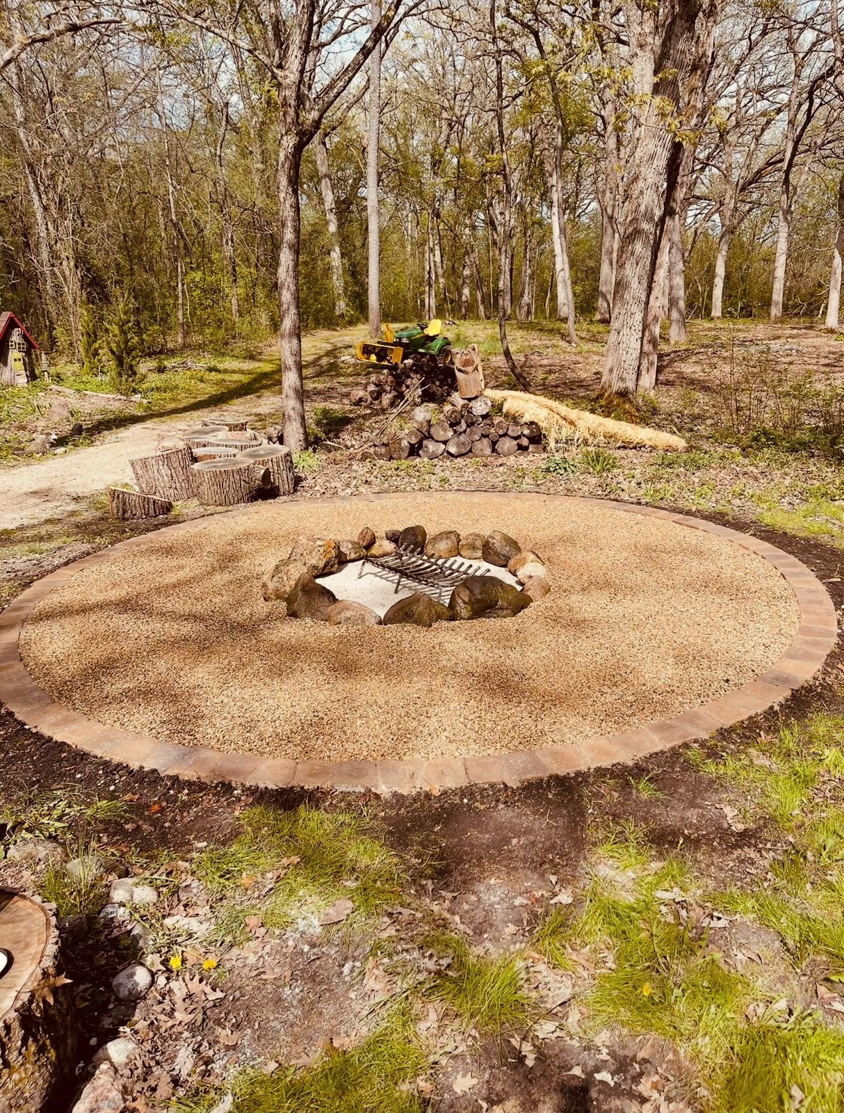 Round stone fire pit with gravel patio among trees