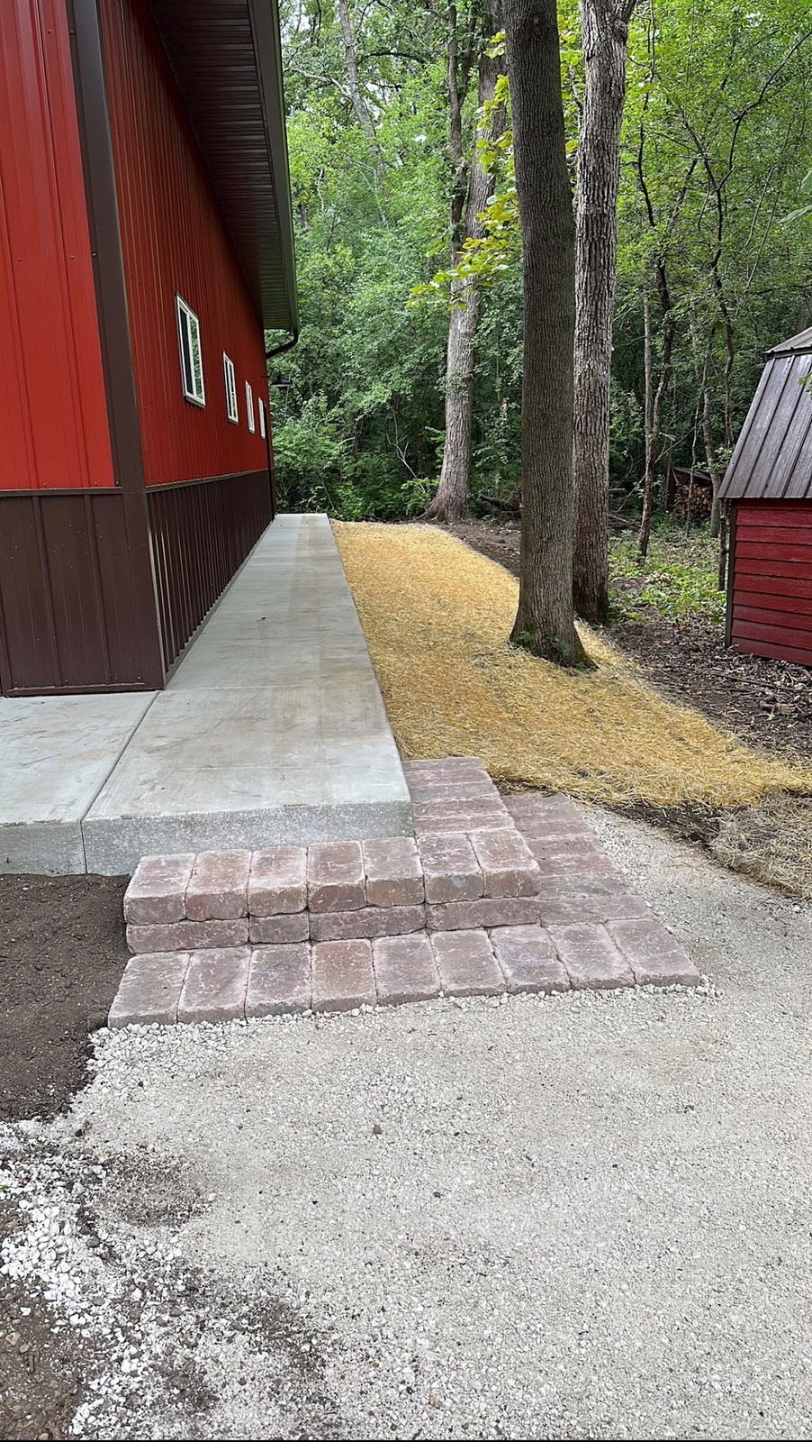 Concrete entrance with paver steps next to a red building