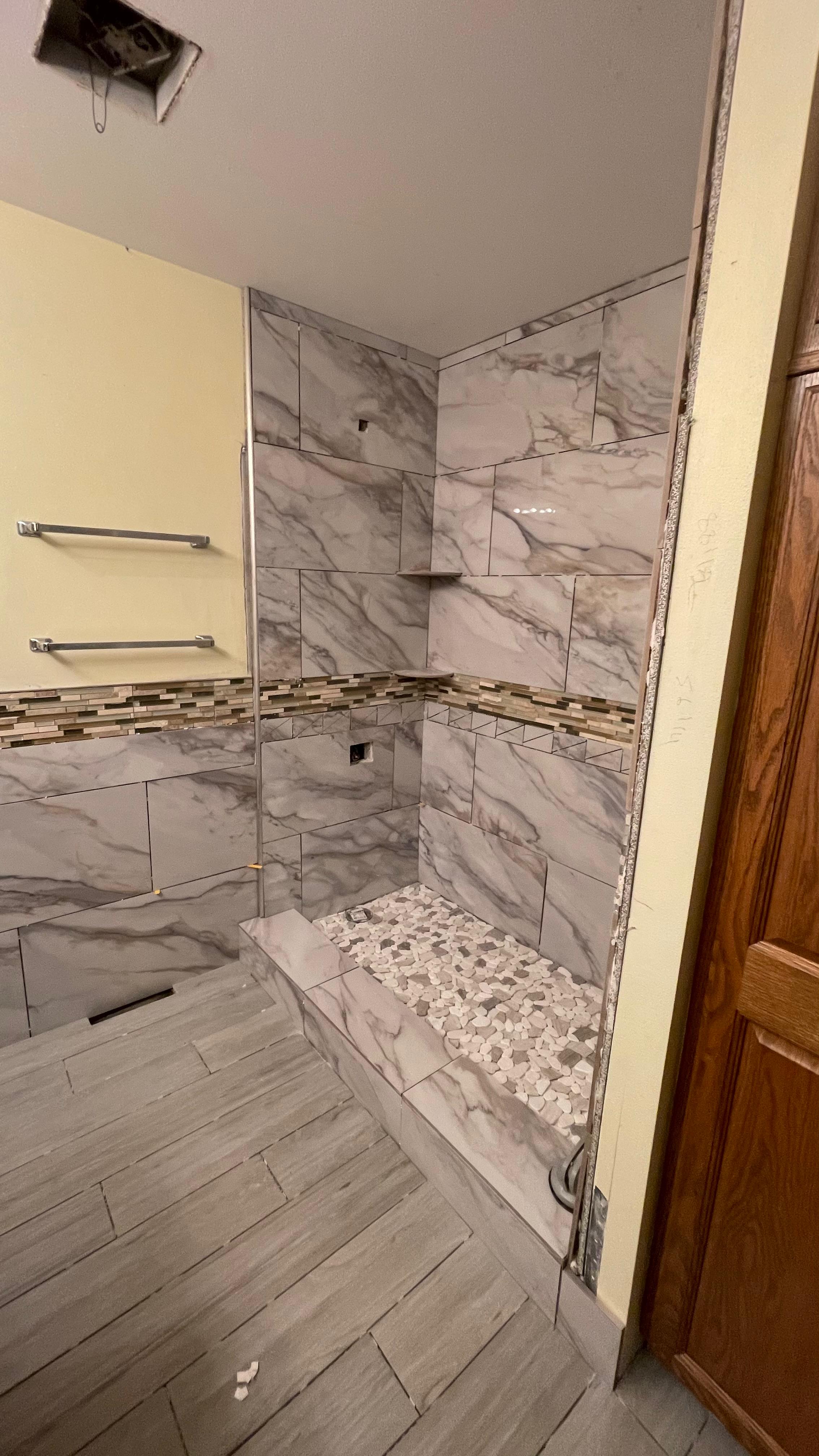 Walk-in tiled shower with mosaic border and pebble base