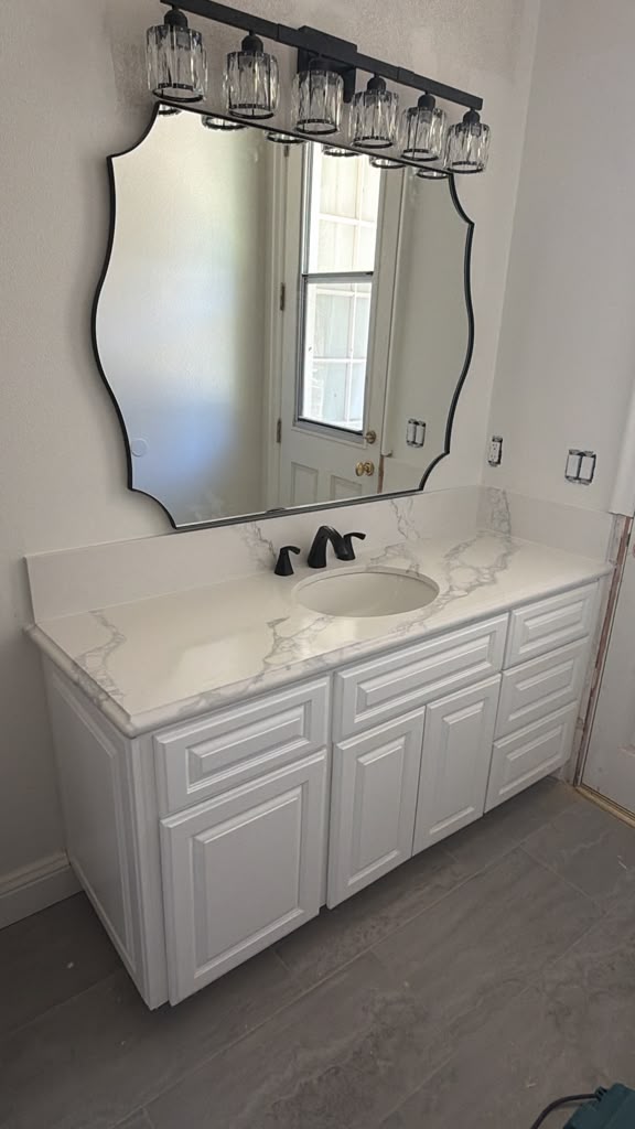 Custom white raised-panel bathroom vanity with calacatta quartz countertop and matte black hardware in Chula Vista CA