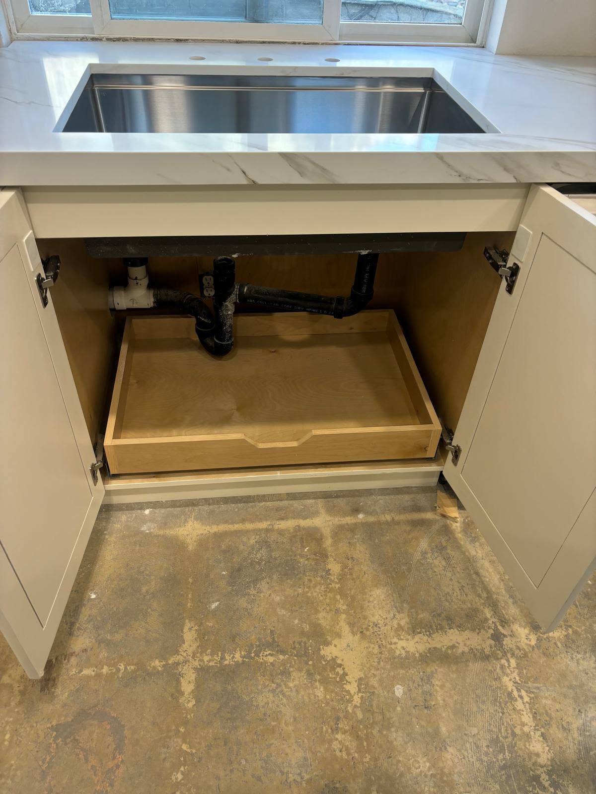 Custom solid wood under-sink pull-out drawer organizer custom-fitted around plumbing by Custom Cabinets San Diego