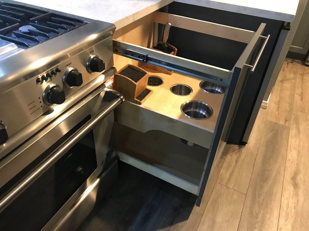 Built-in pull-out stainless steel utensil canister and knife block organizer cabinet beside range