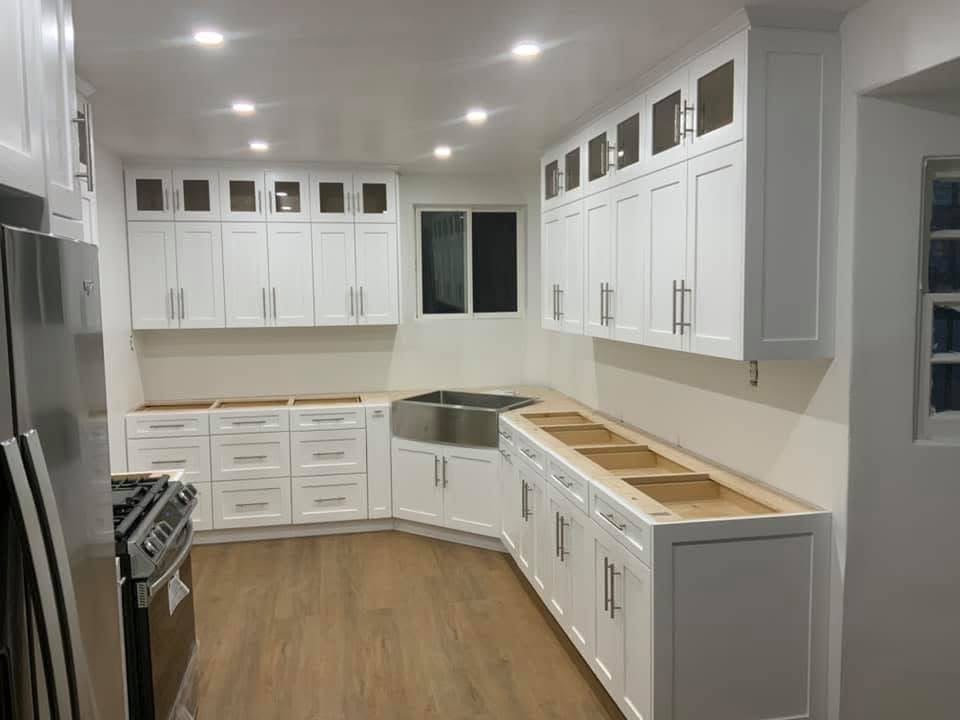 Custom white shaker kitchen cabinetry with upper lighted glass transom display cabinets and farmhouse apron sink