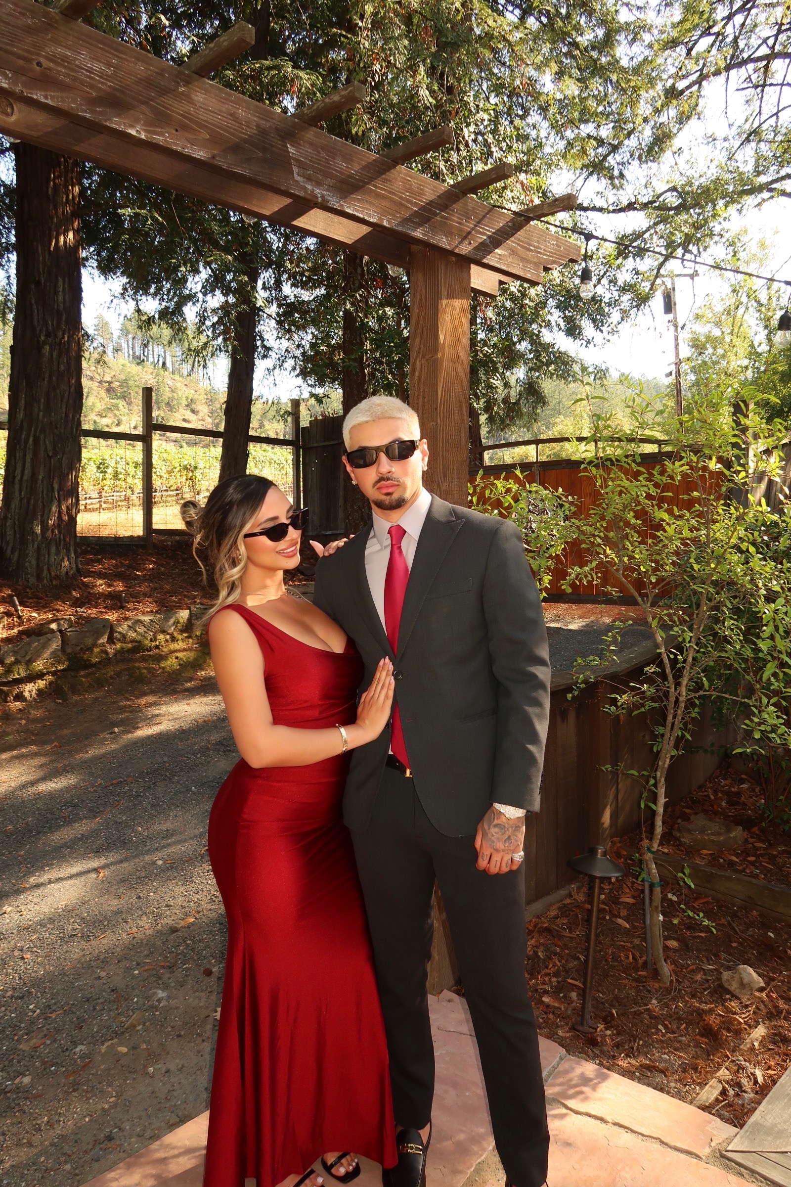 Justin Guerra in tailored black suit with partner in red gown at private estate