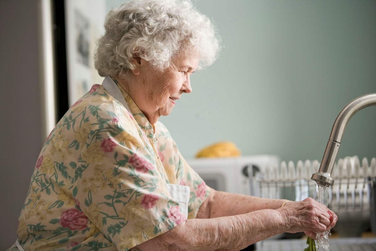 An adult daughter sitting alongside her older mother while a supportive caregiver assists nearby