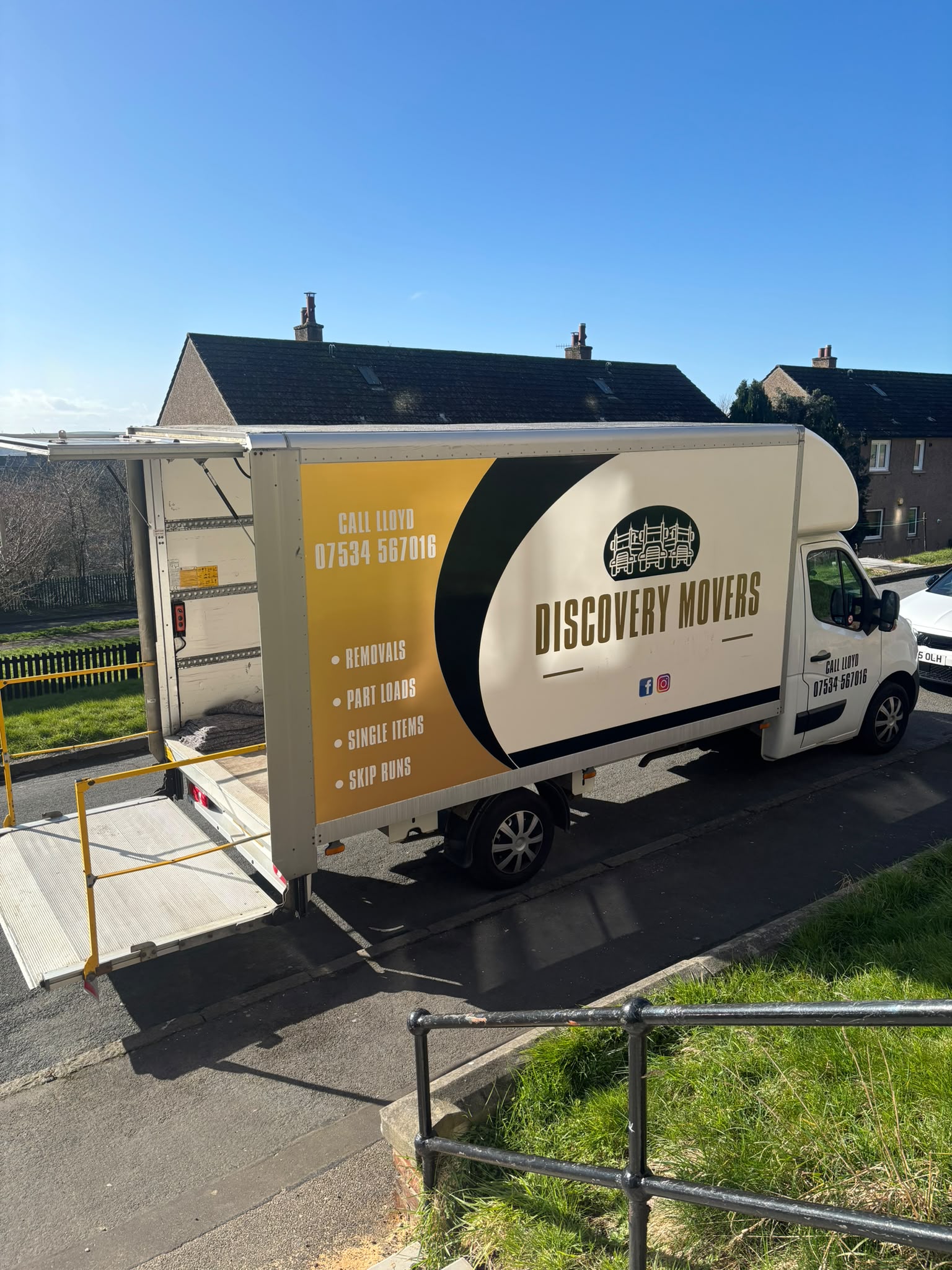 Discovery Movers removal truck with tail lift open outside houses