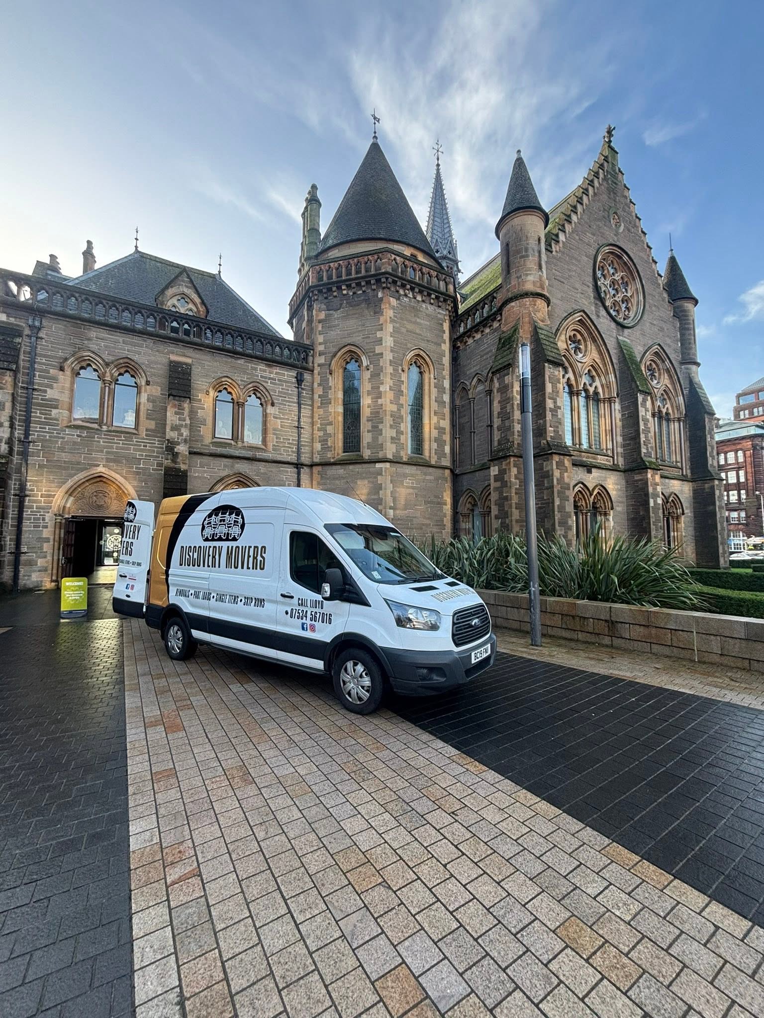 Discovery Movers branded removal van parked outside a historic stone building in Dundee