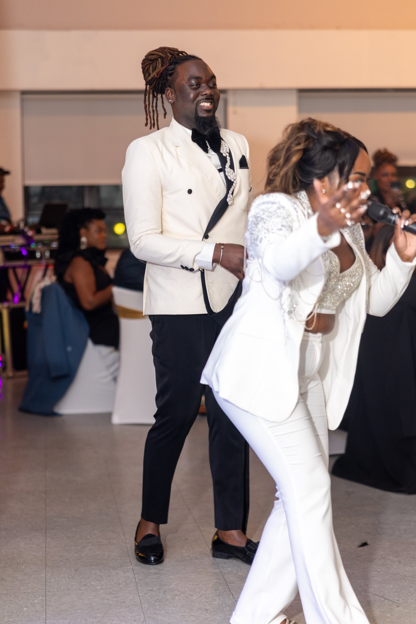 Taje hyping up the dance floor in white embellished suit with guests