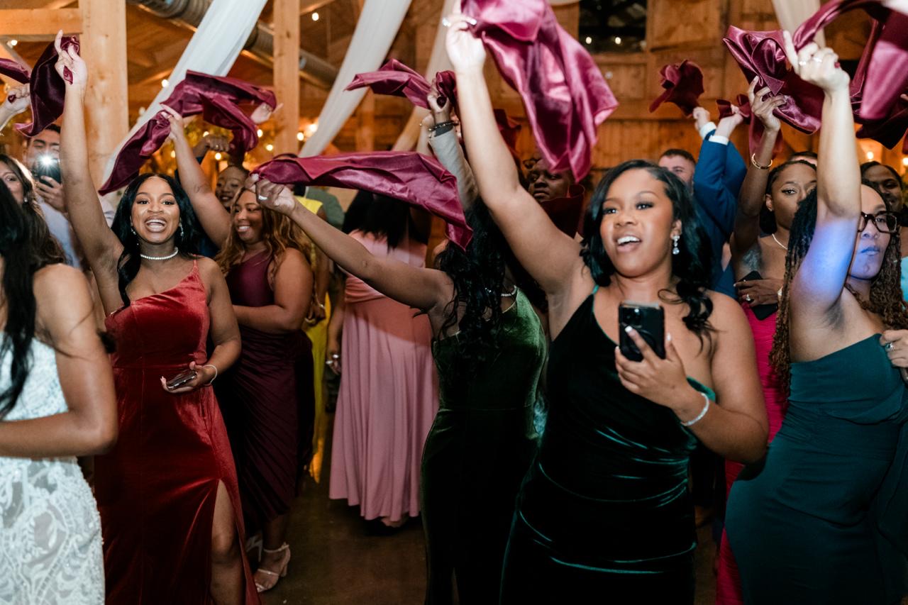 Wedding guests waving burgundy satin napkins in vibrant celebration