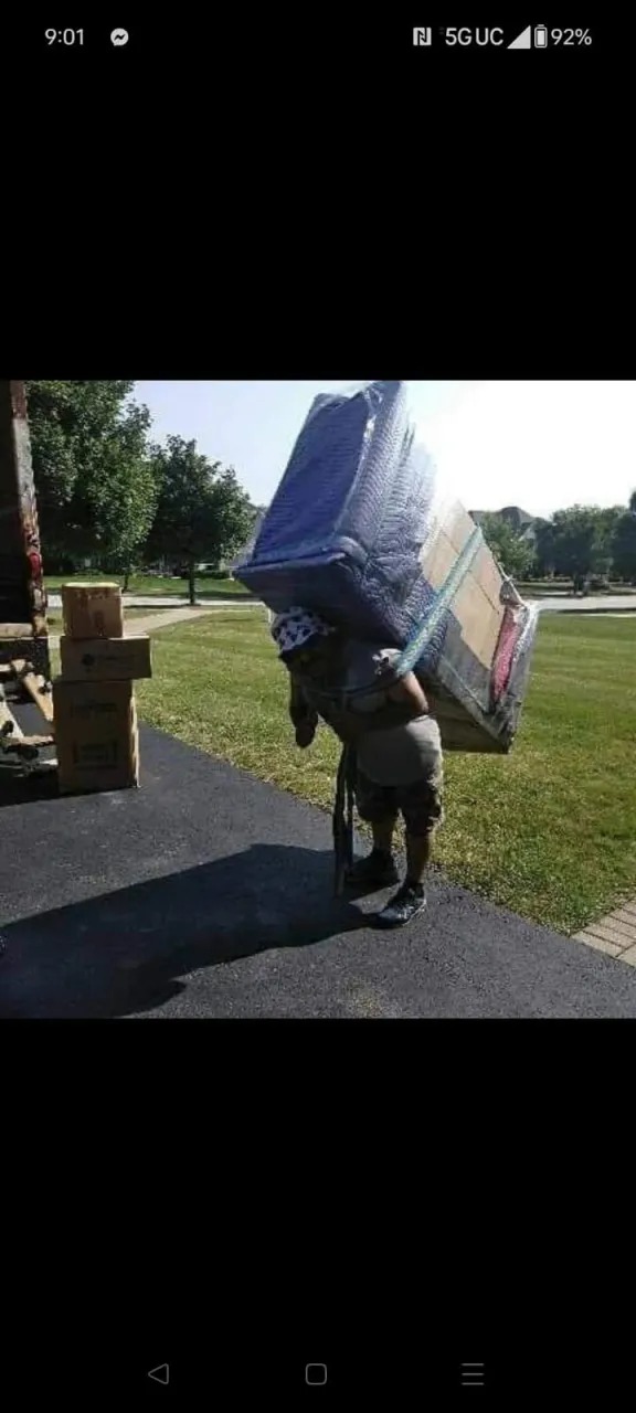 Two movers carrying a heavy wrapped sofa with moving straps in Chicagoland
