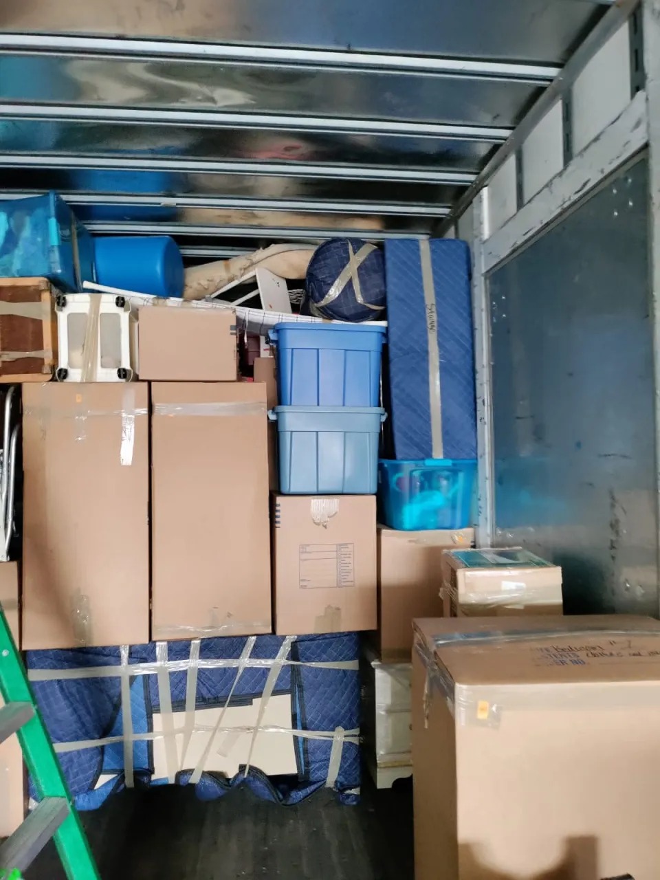 Interior of moving truck stacked to the ceiling with blue totes and blankets in Chicago