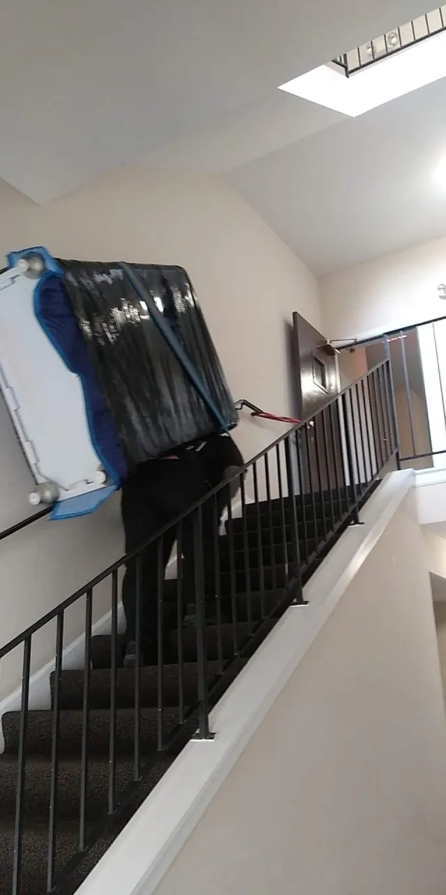 Mover using a shoulder harness to carry furniture down narrow stairs in Naperville