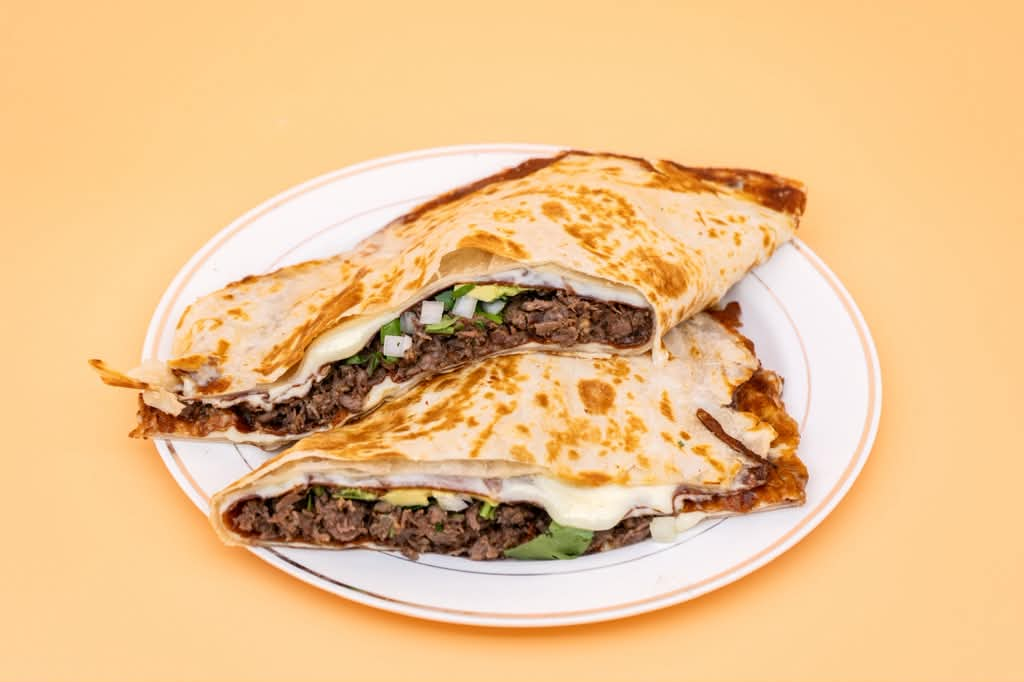 Quesadilla Mega dorada rellena de queso derretido, carne, cebolla y cilantro