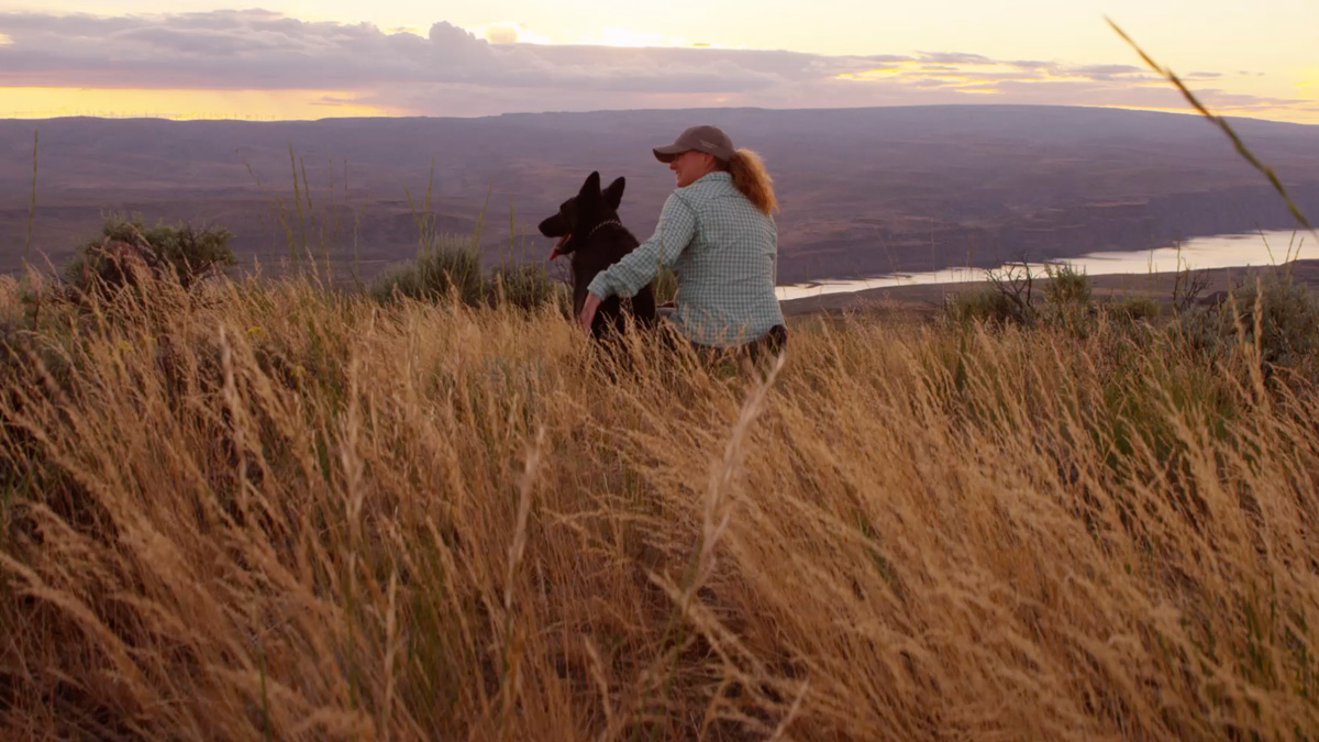 Trainer and dog looking out over scenic canyon