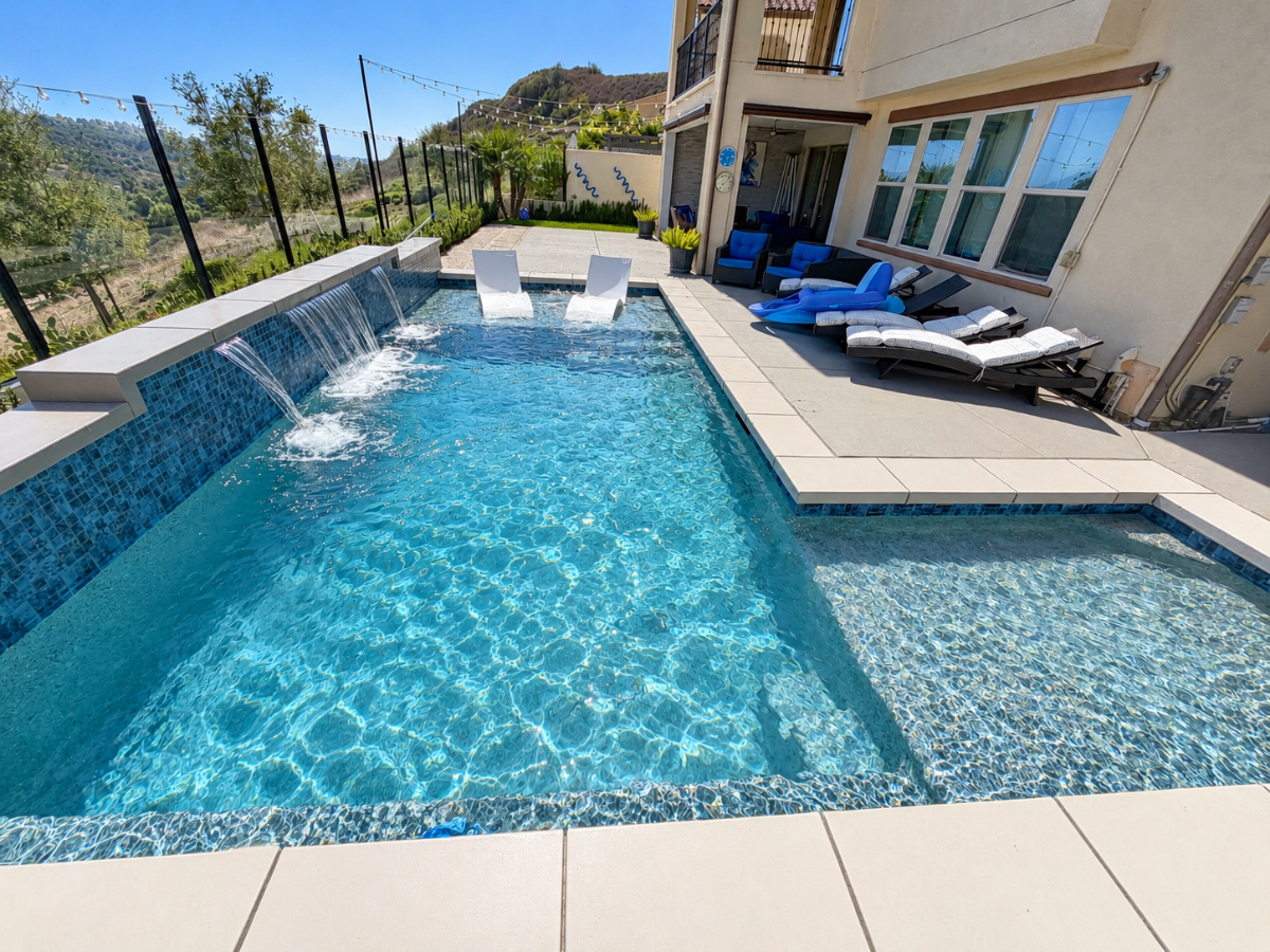 Sparkling clean swimming pool with water features and lounge chairs overlooking scenic hills