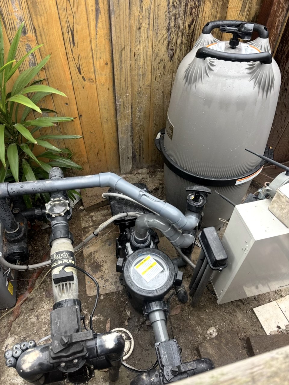 Pool filter and circulation pump equipment setup along backyard fence