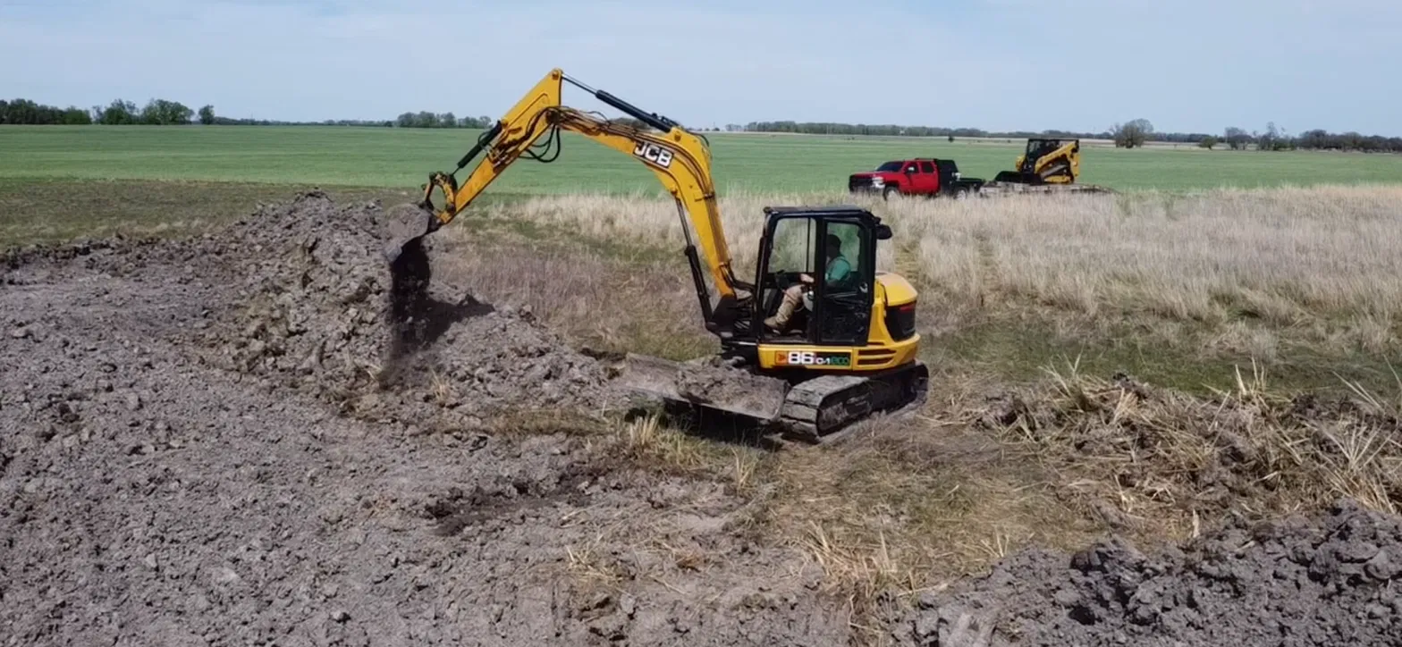 JCB excavator digging and stockpiling soil