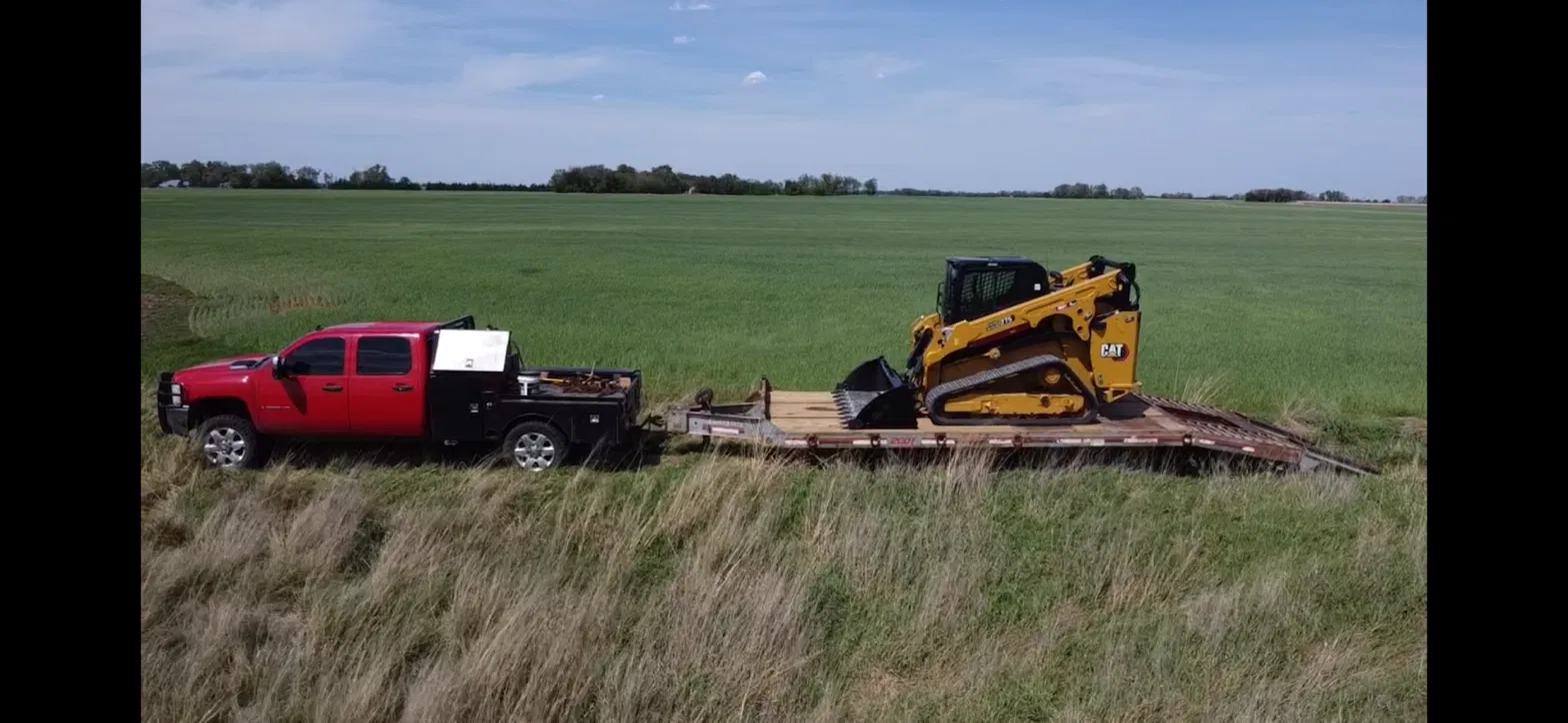 Baker Industries truck and trailer hauling a CAT compact track loader