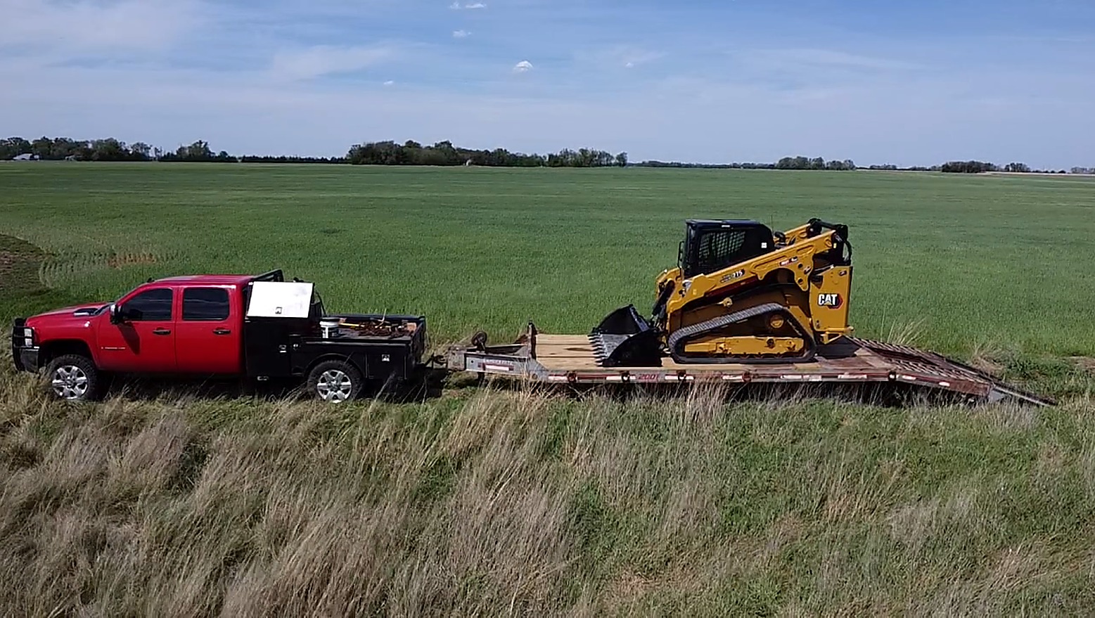 Baker Industries truck and trailer hauling a CAT compact track loader