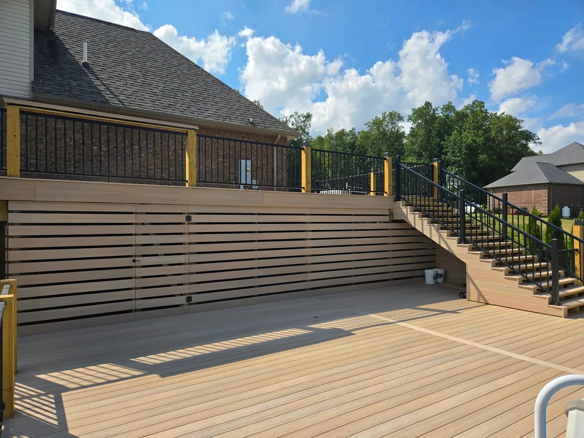 H&H Home & Bath Renovations multi-level composite deck with custom horizontal privacy skirt, black railings, and wide staircase
