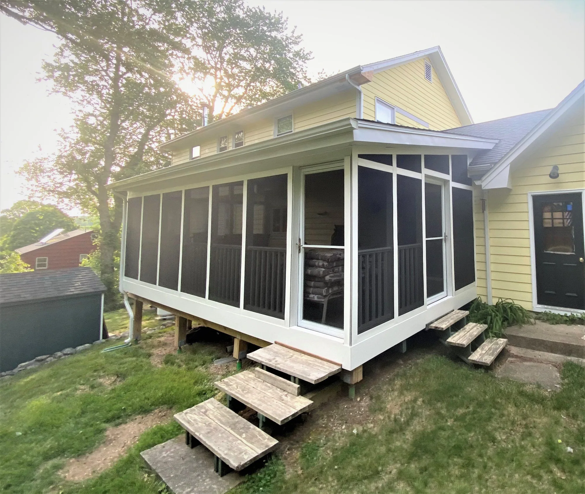H&H Home & Bath Renovations completed custom screened-in sunroom porch addition with white framing, screen panels, storm door, and wooden entry steps