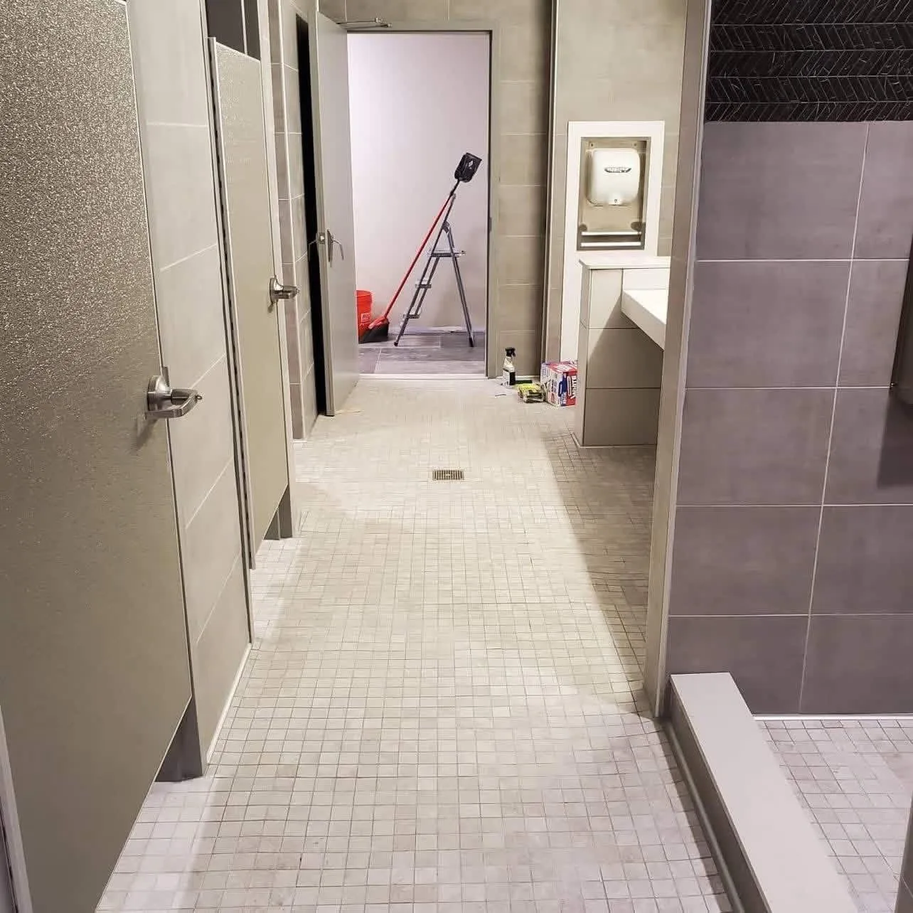 H&H Home & Bath Renovations commercial tile flooring installation with mosaic floor tiles, floor drain, and grey wall tile surround