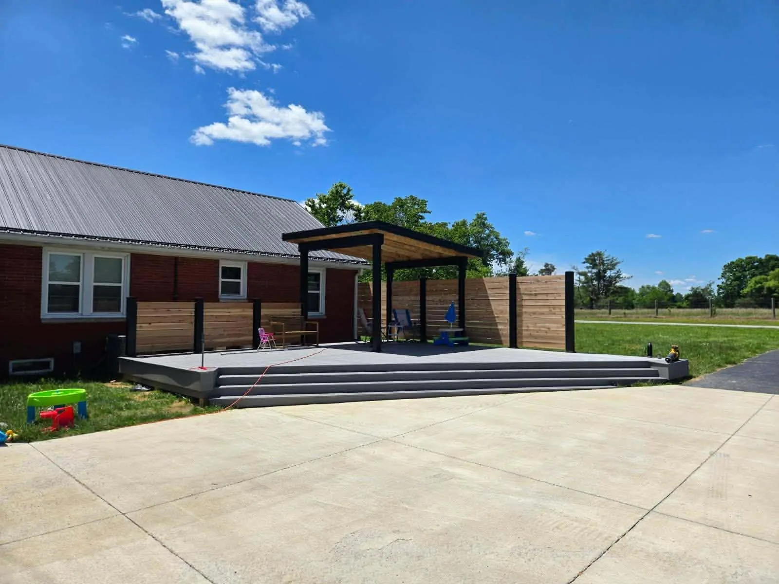 H&H Home & Bath Renovations custom modern outdoor pavilion deck with horizontal cedar privacy wall and wide tiered steps