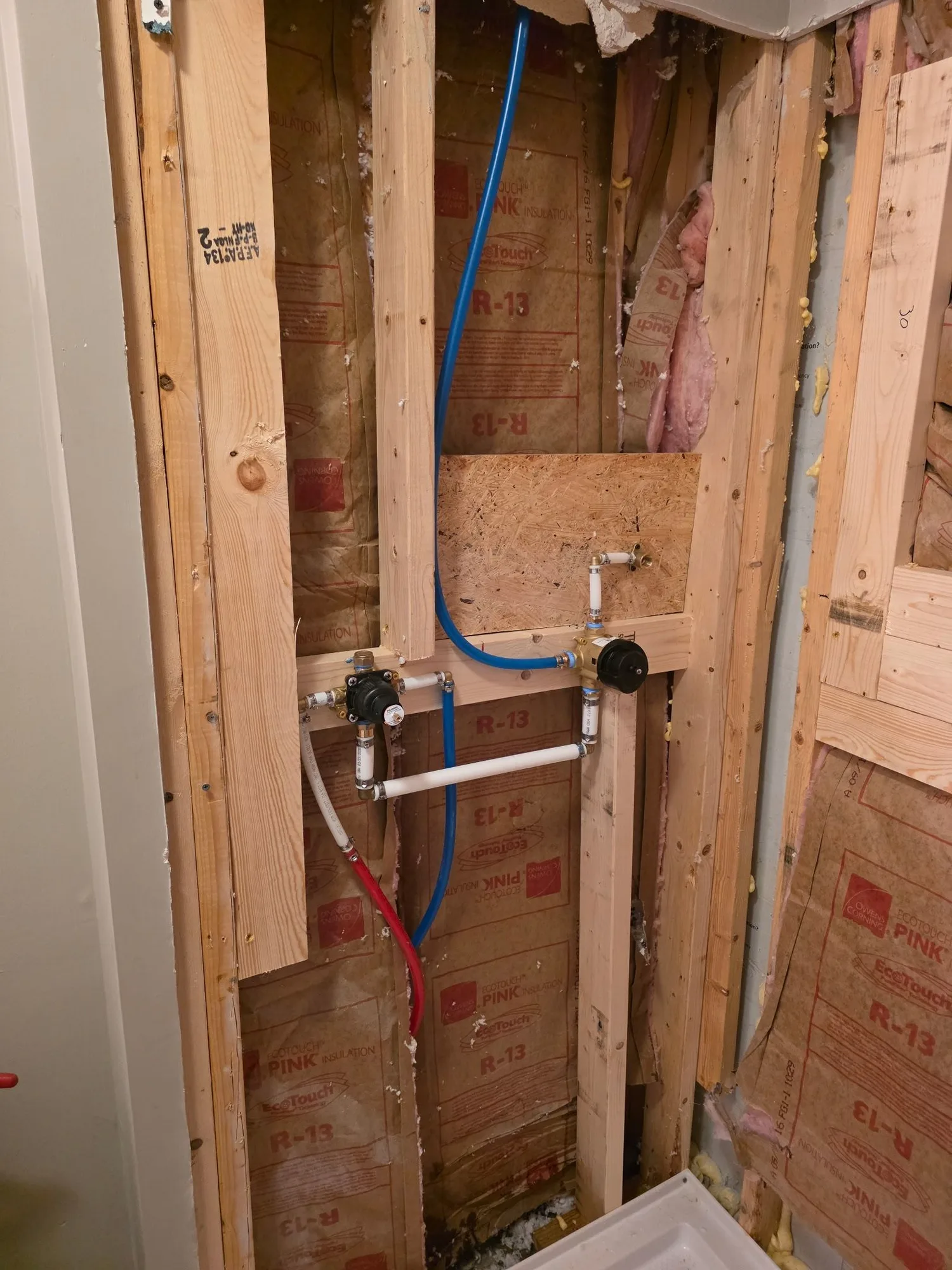 H&H Home & Bath Renovations in-progress shower valve plumbing rough-in with PEX supply lines and pressure-balance controls framed in wall studs
