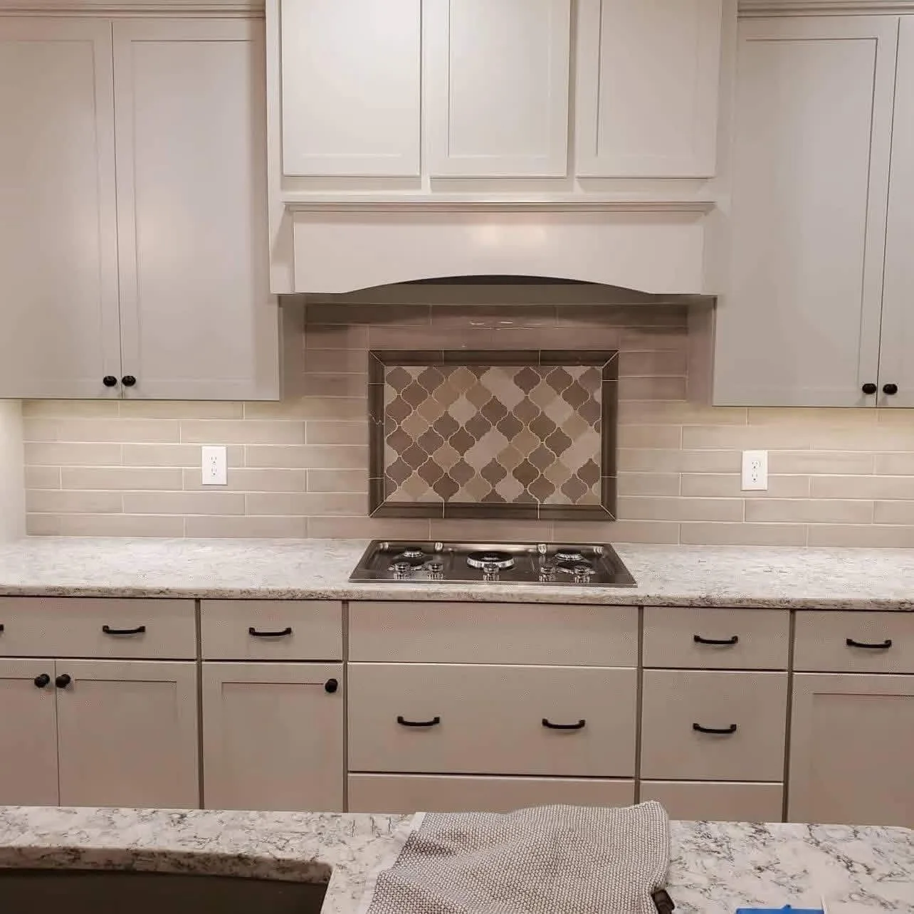 H&H Home & Bath Renovations custom kitchen remodel with white shaker cabinets, decorative tile range backsplash, custom hood, and granite countertops